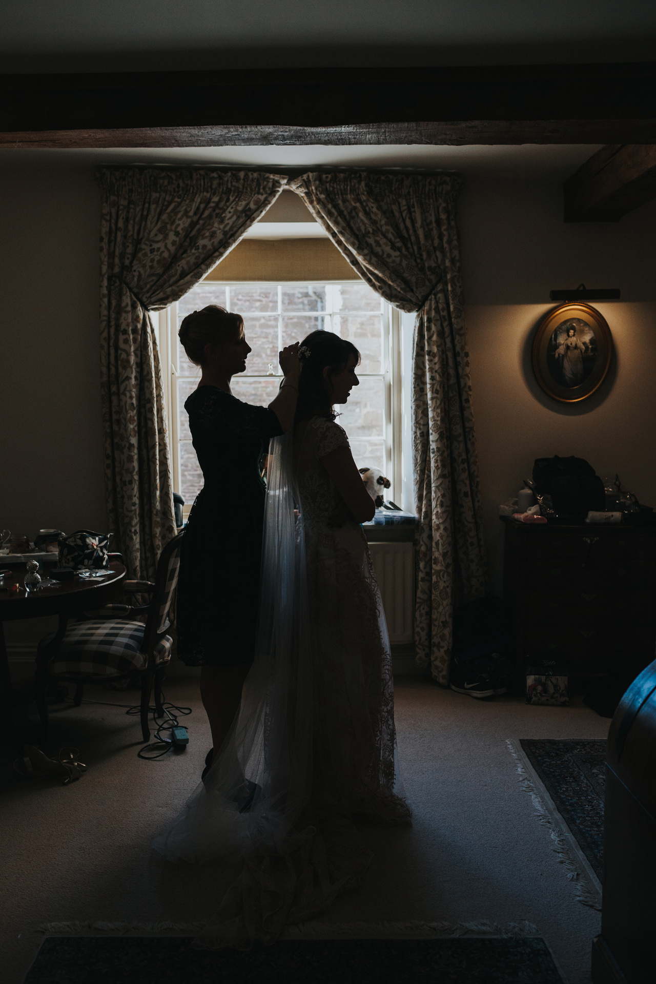 Silhouette of bride getting her veil put on. 