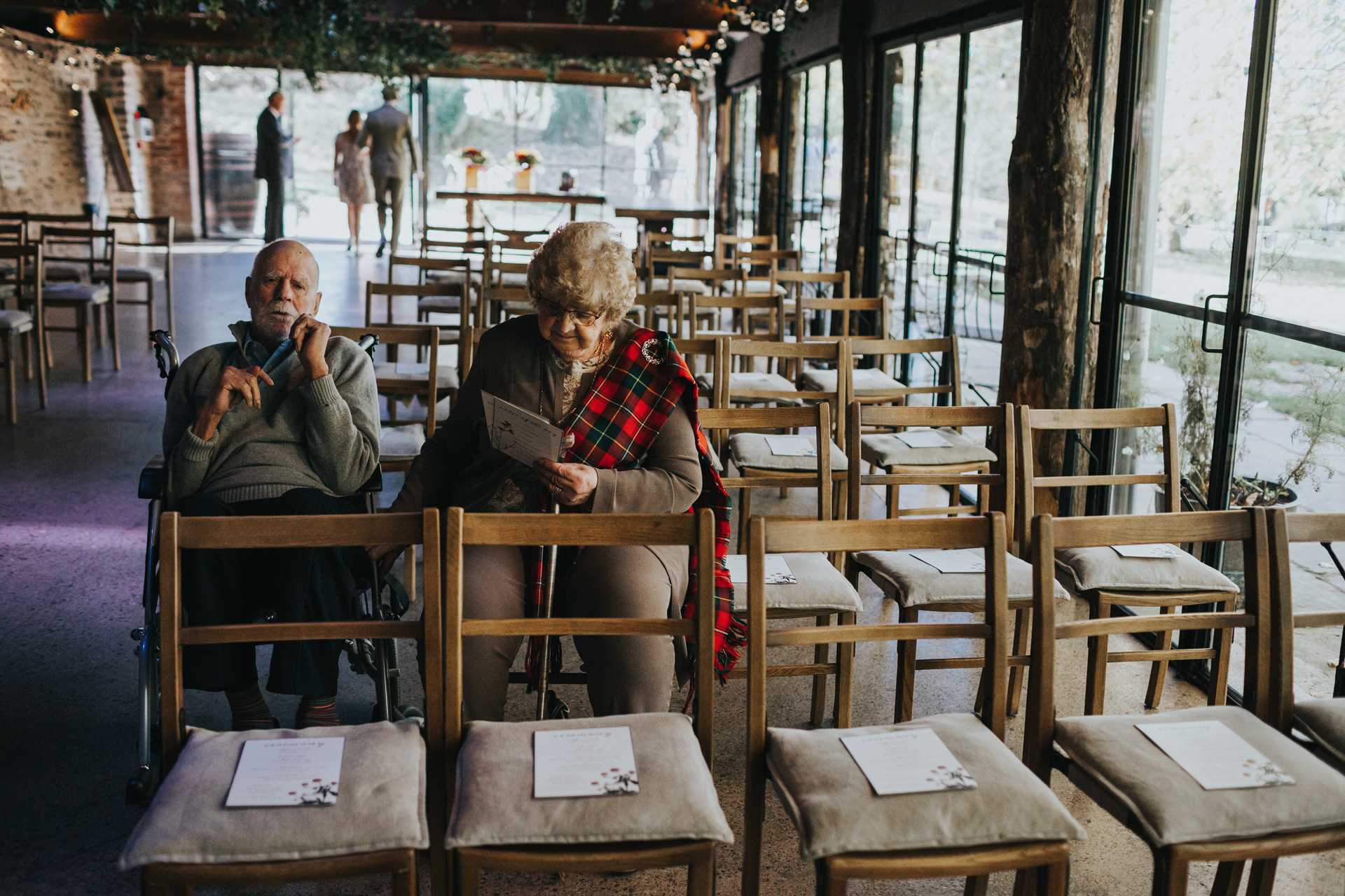 Wedding guests wait in their chairs as other guests arrive. 