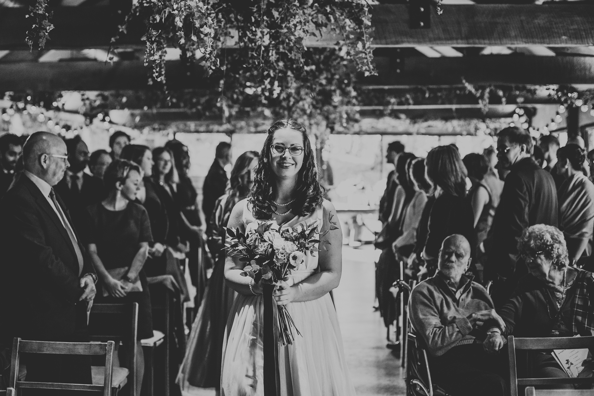 Bridesmaid walking down the aisle smiling.