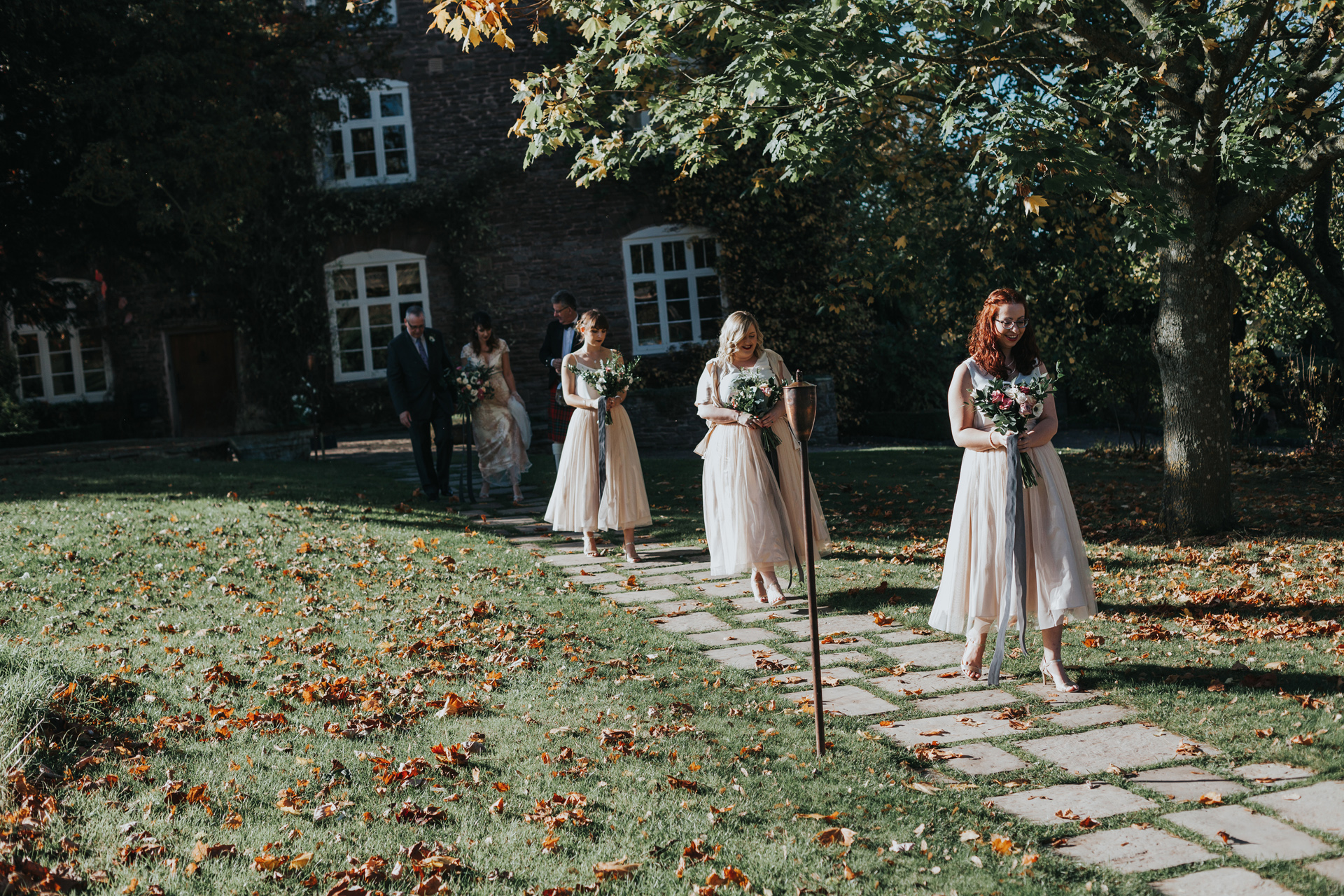 The bridesmaids lead the way across the lawn towards the ceremony room. 