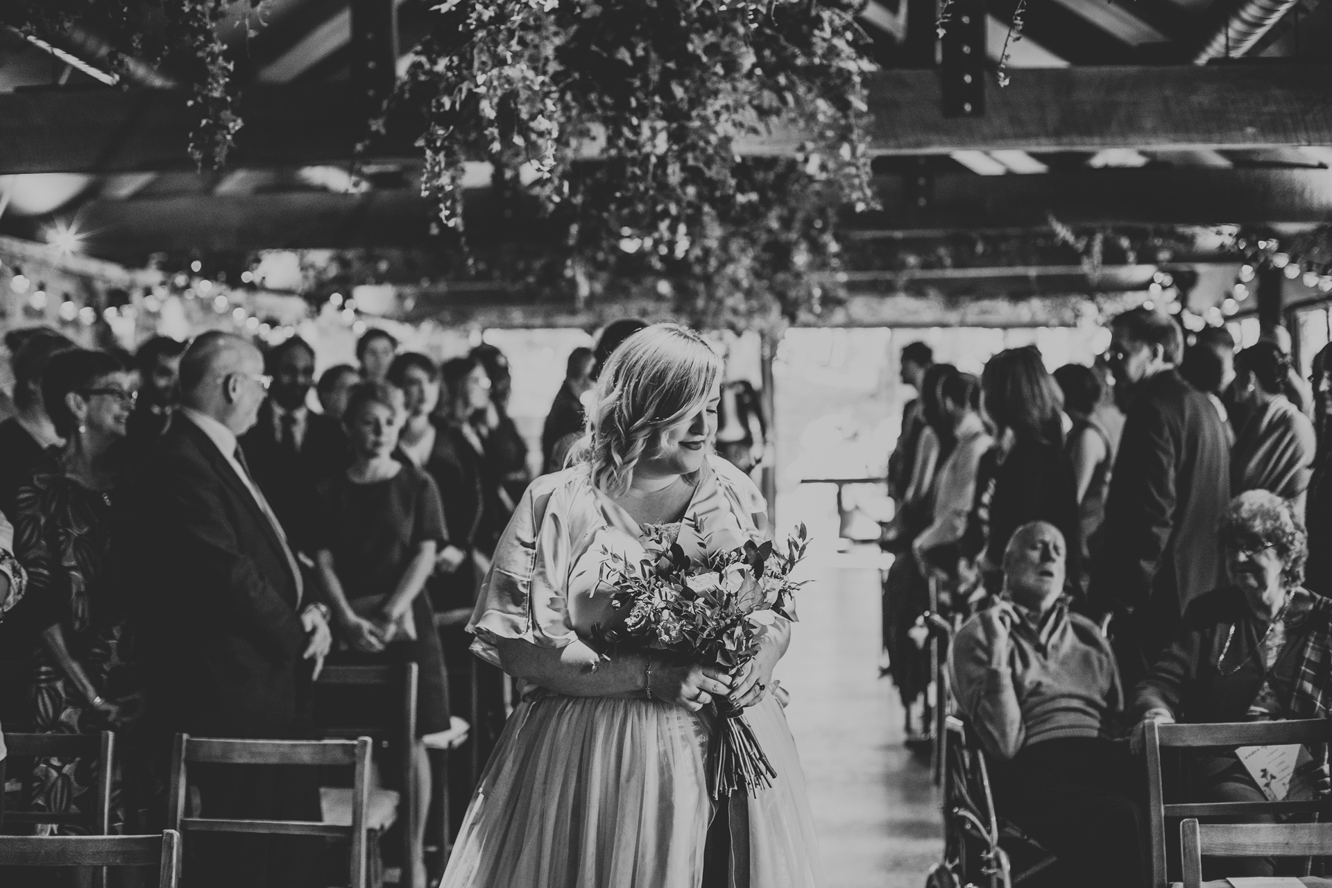 Bridesmaid arrives at bottom of the aisle, photograph in black and white. 