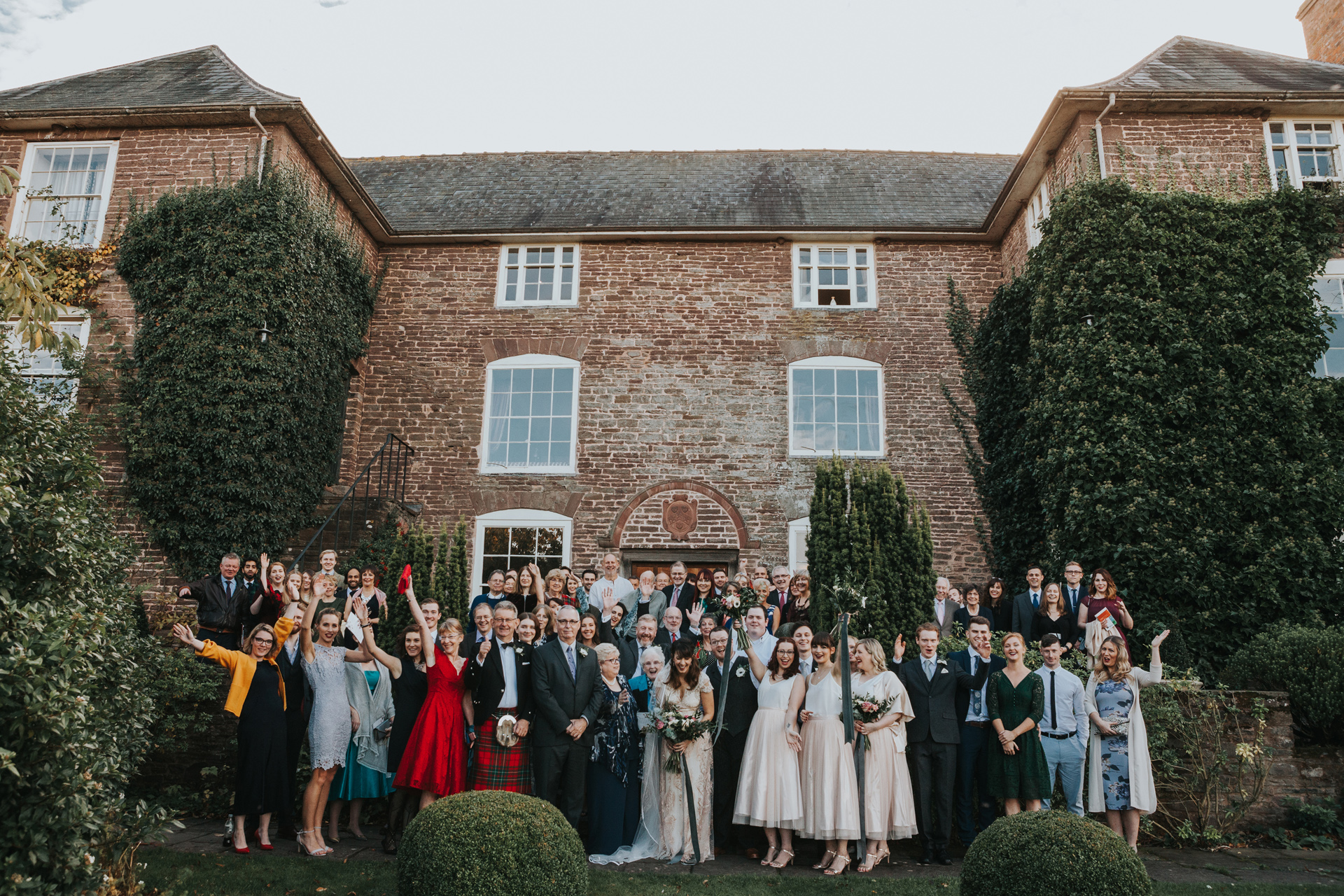 Group photograph of all wedding guests in front of the main house at Dewsall Court.