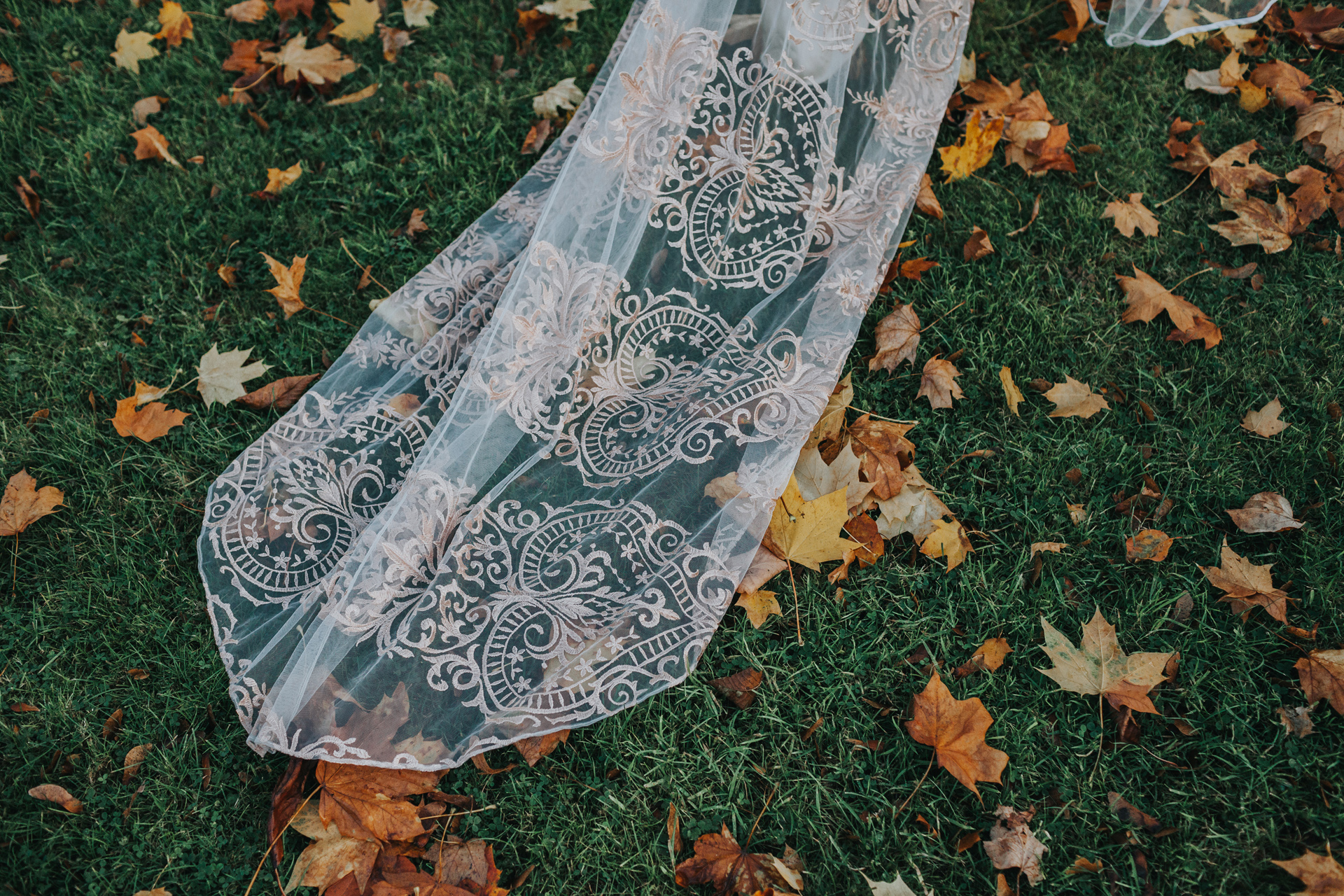 Brides dress trails in autumn leaves. 