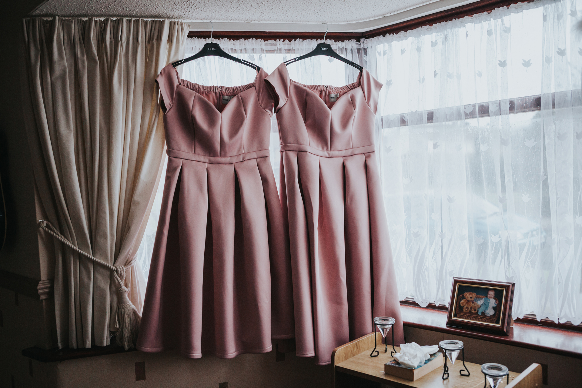 Bridesmaid dresses hanging in the window.