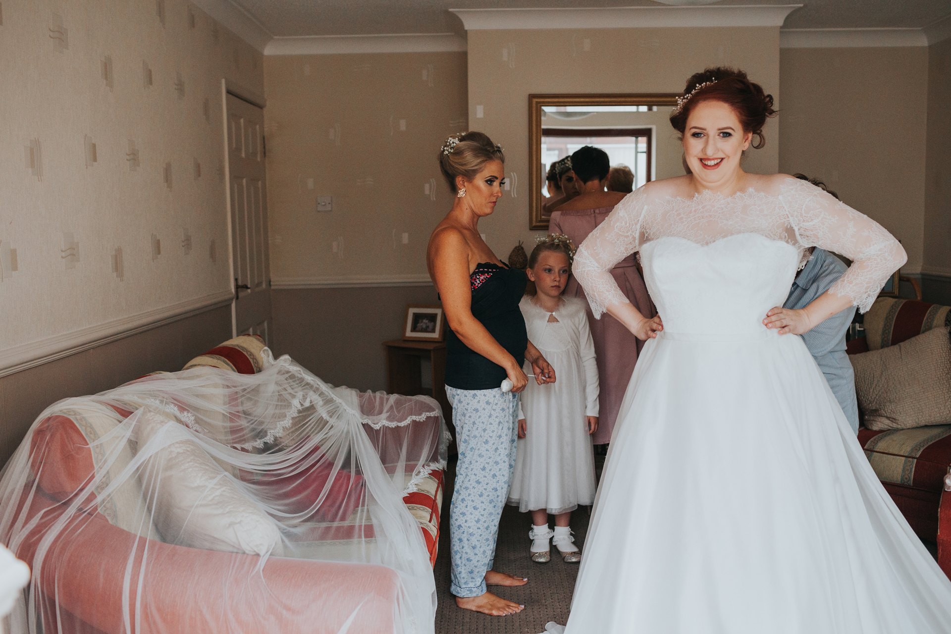 Bride stood next to veil on sofa. 