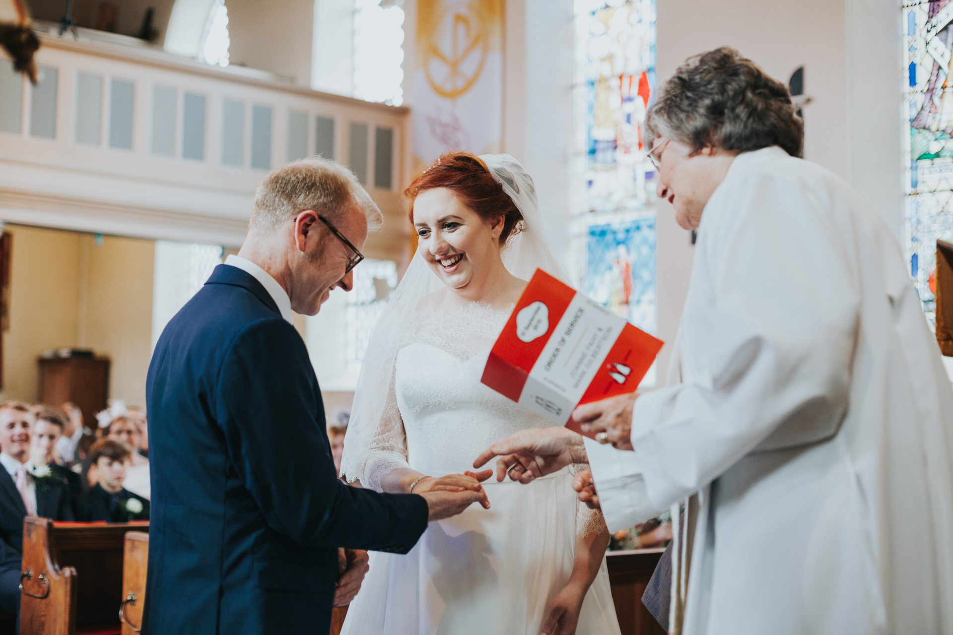 Bride and groom look at one and other smiling as they exchange rings.