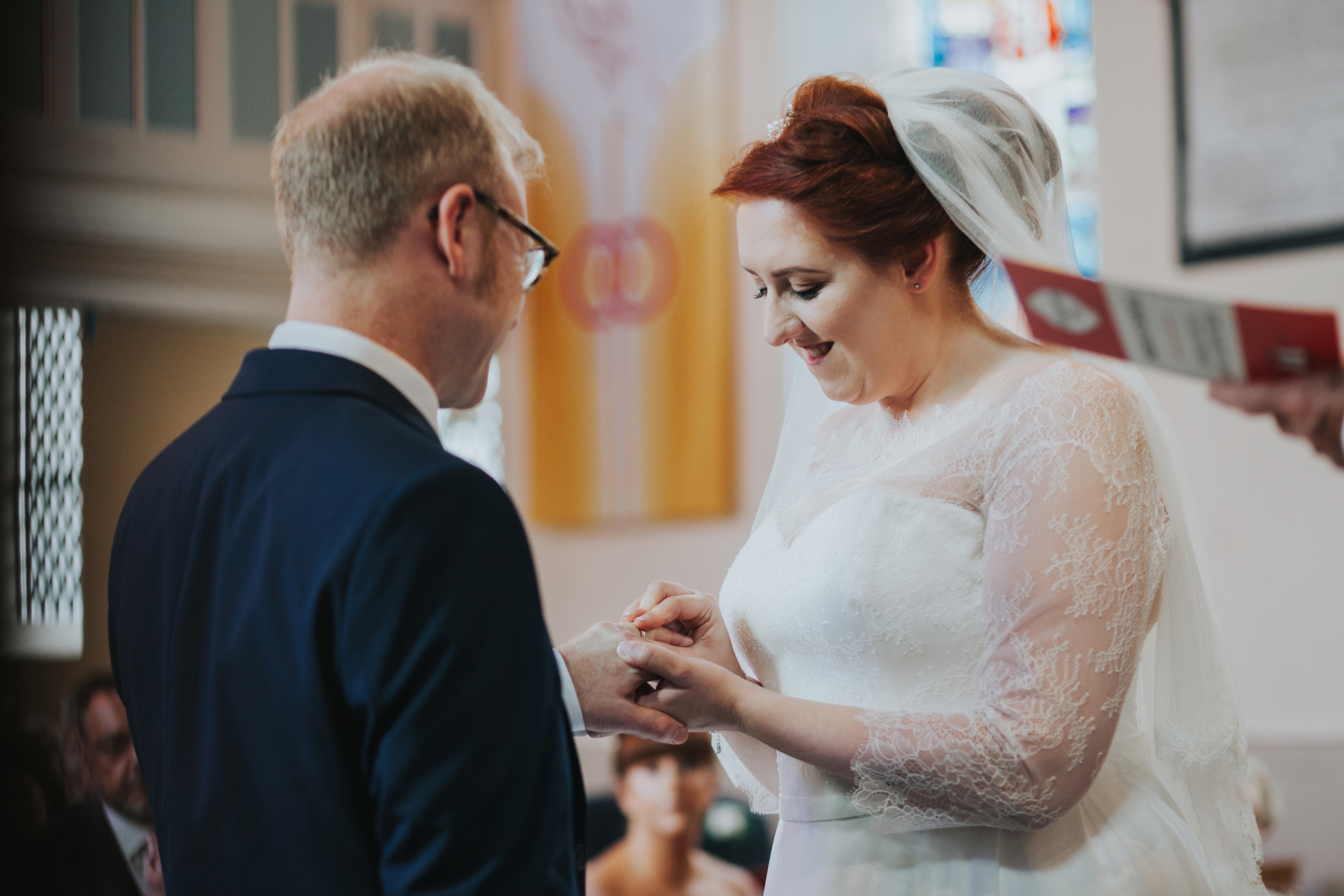 Bride puts ring on grooms finger.