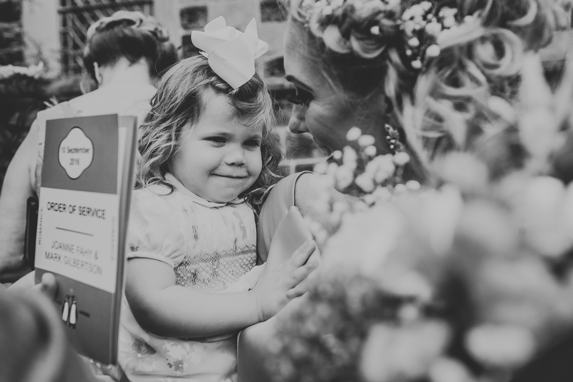 Little girl gets a cuddle from a bridesmaid.