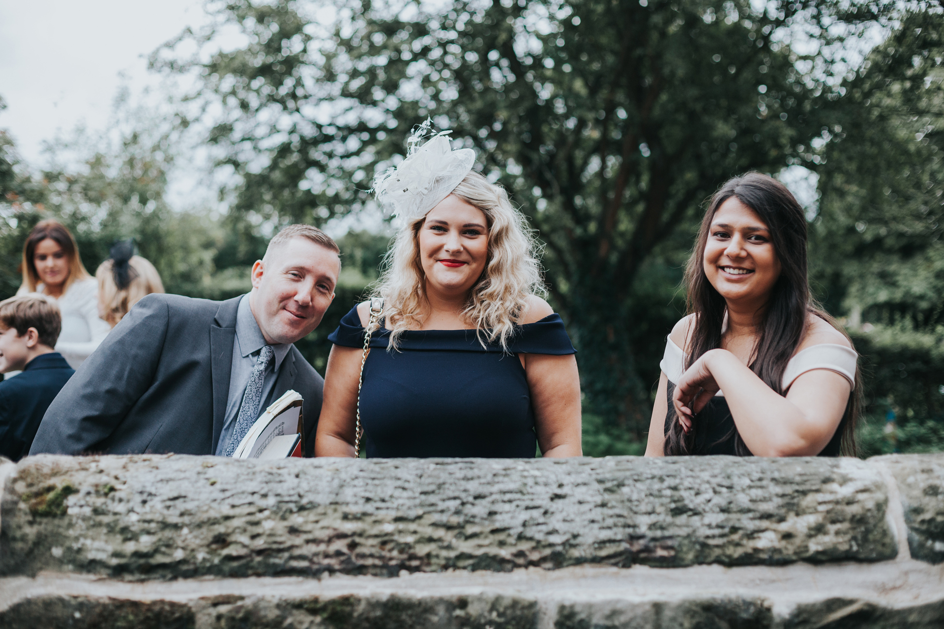 Guests smile over church wall.