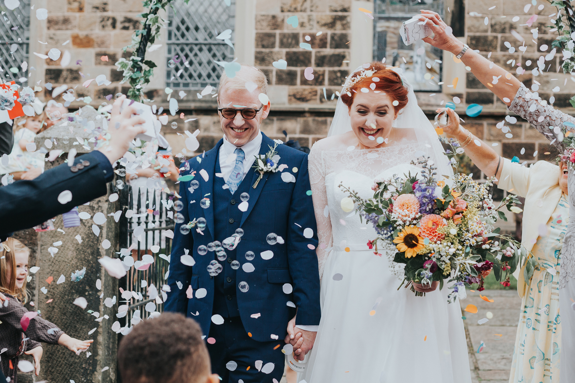 Bride and groom make their way through the confetti.