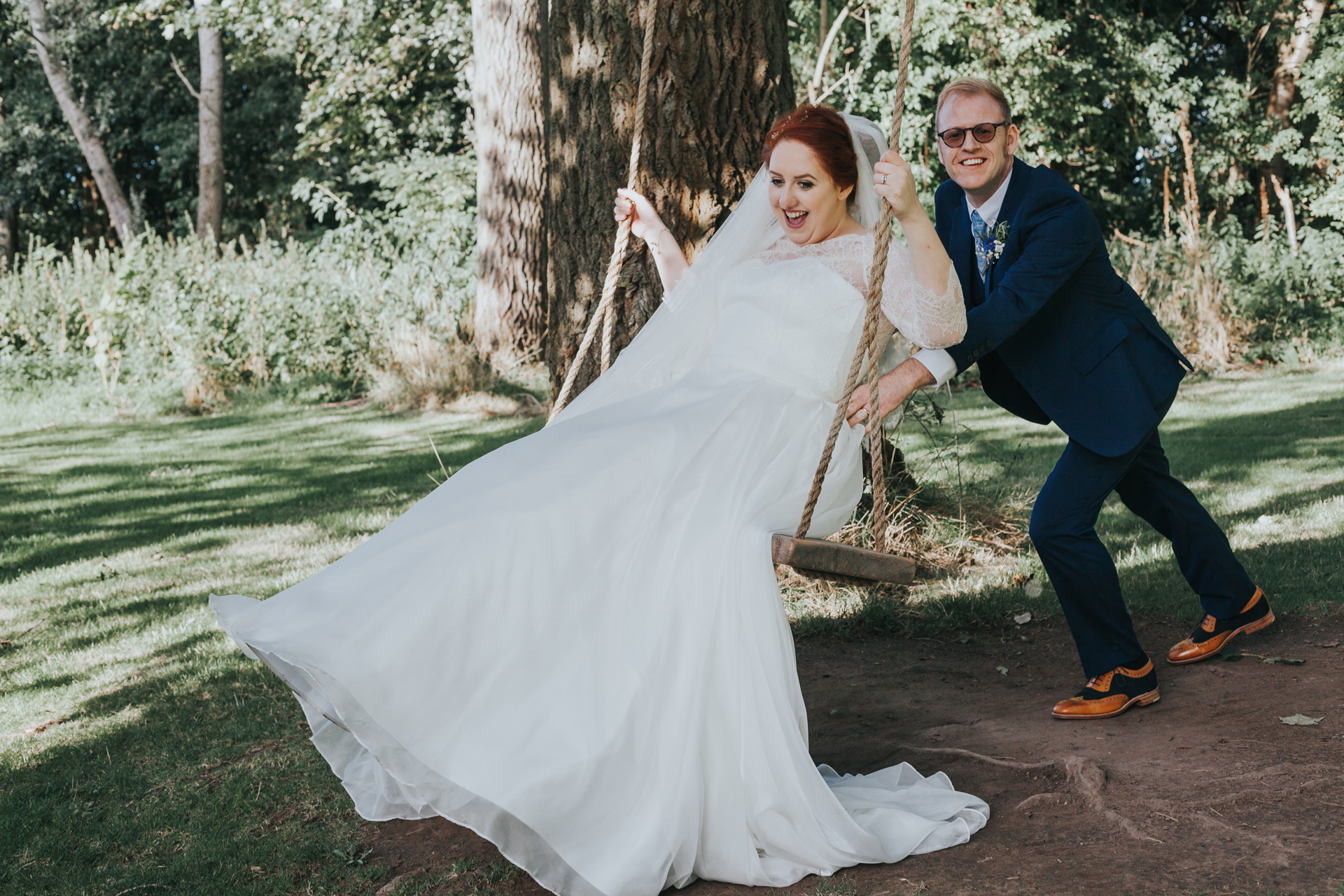 Groom pushes bride on swing at Trafford hall. 