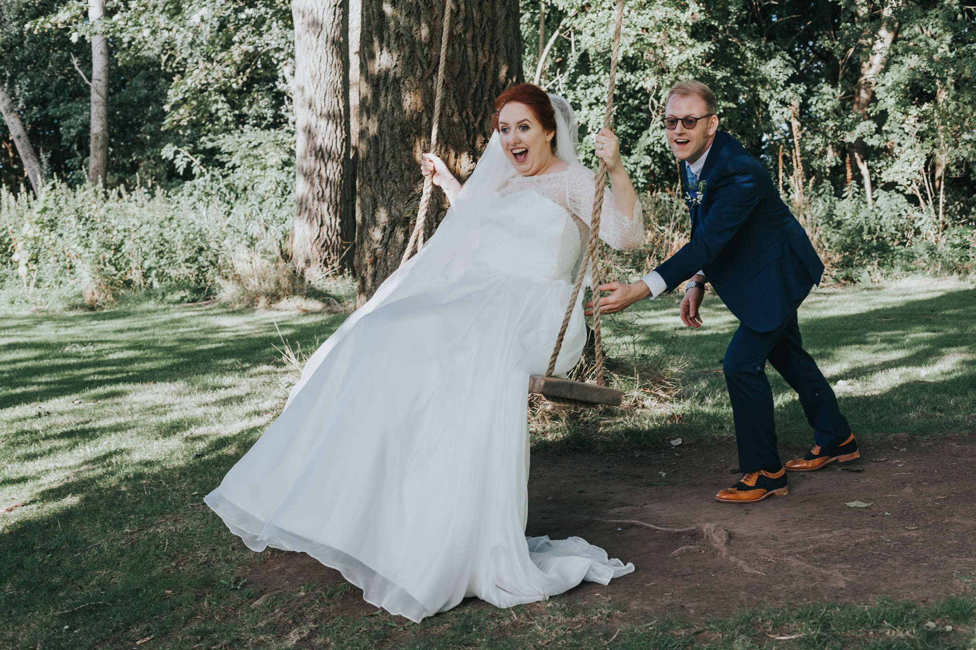 Groom pushes bride on swing. 