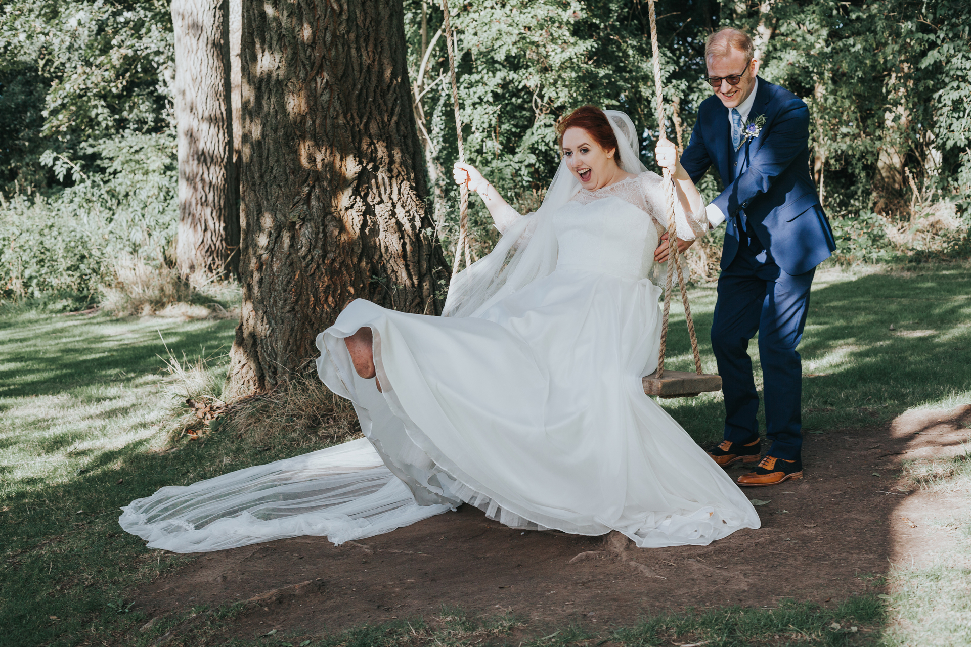 Bride and groom play on tree swing at Trafford Hall. 