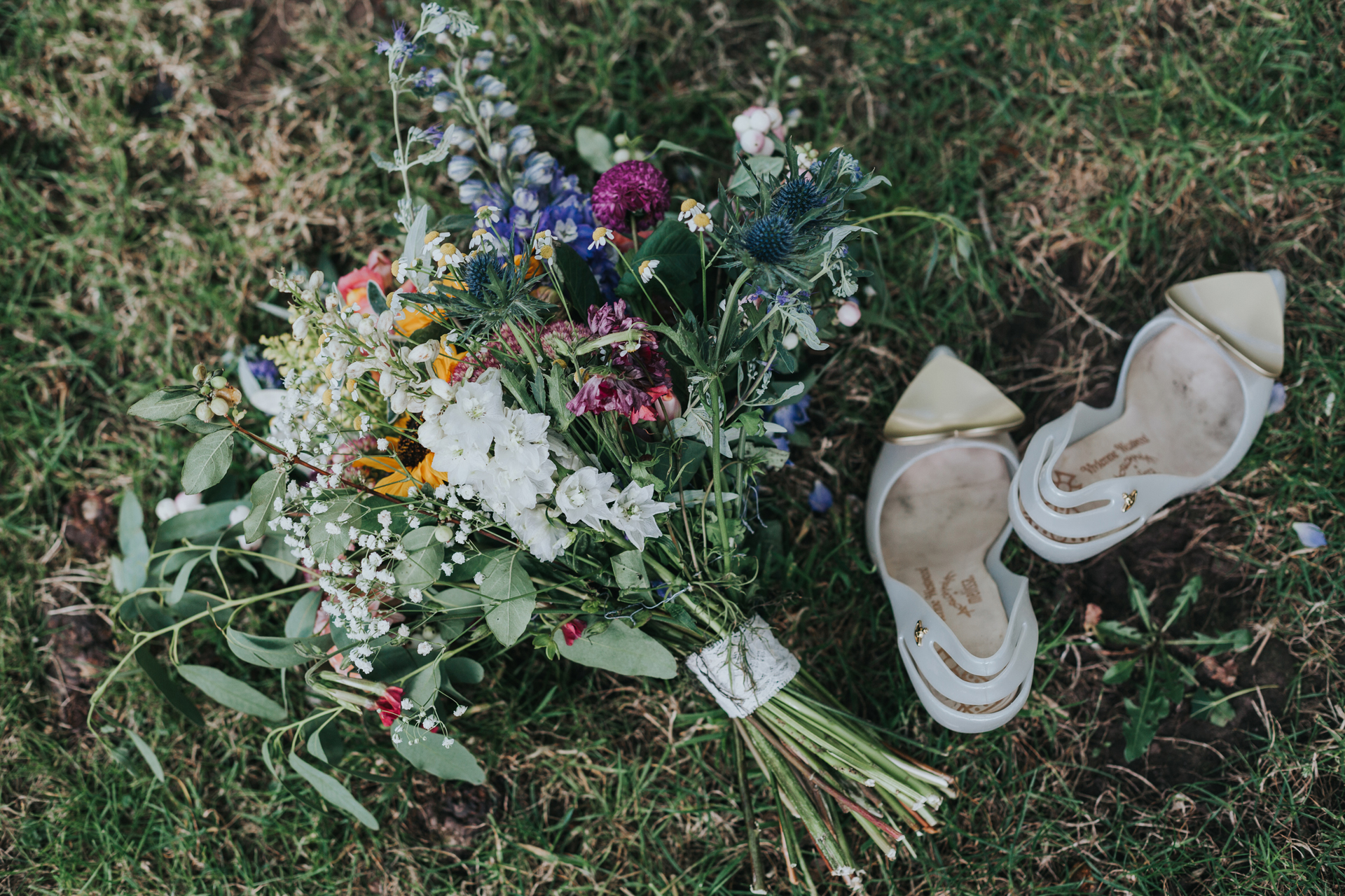 Brides flowers and shoes lying on the grass.