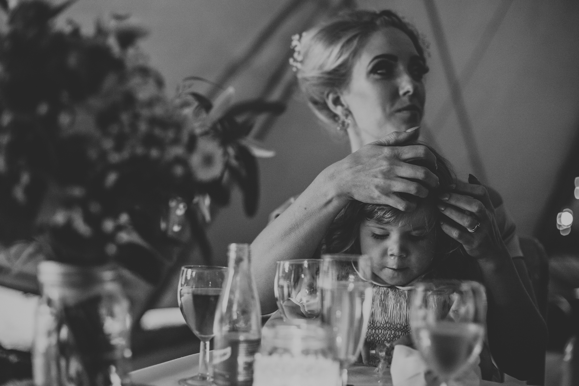 Bridesmaid plays with her daughters hair.