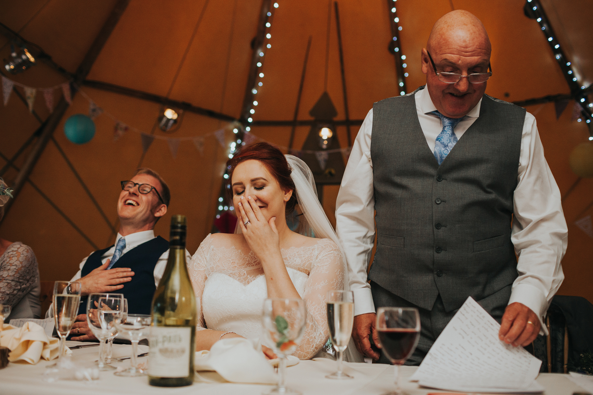 Bride and groom laughing at speech. 