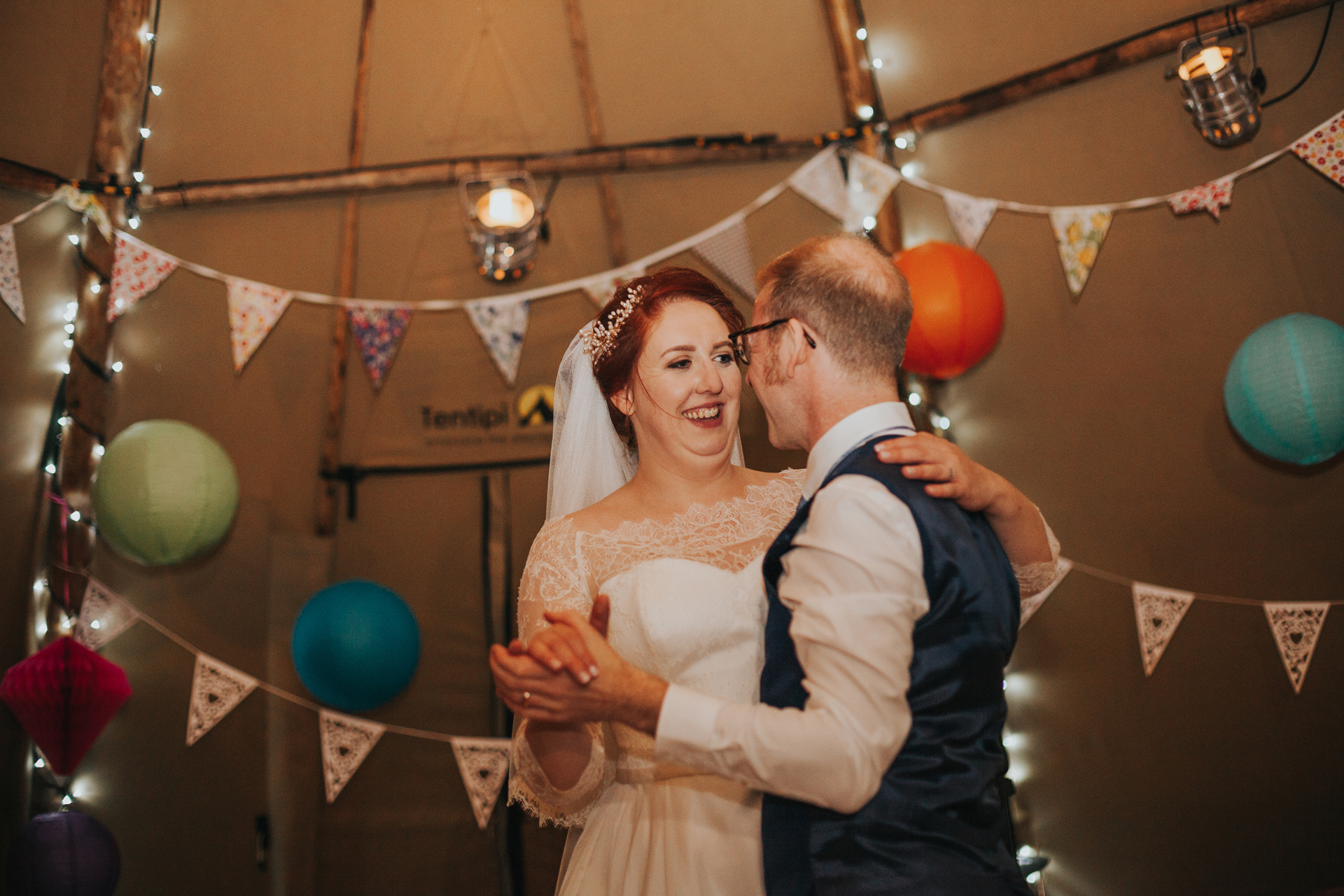 Bride looking at groom smiling while they dance. 