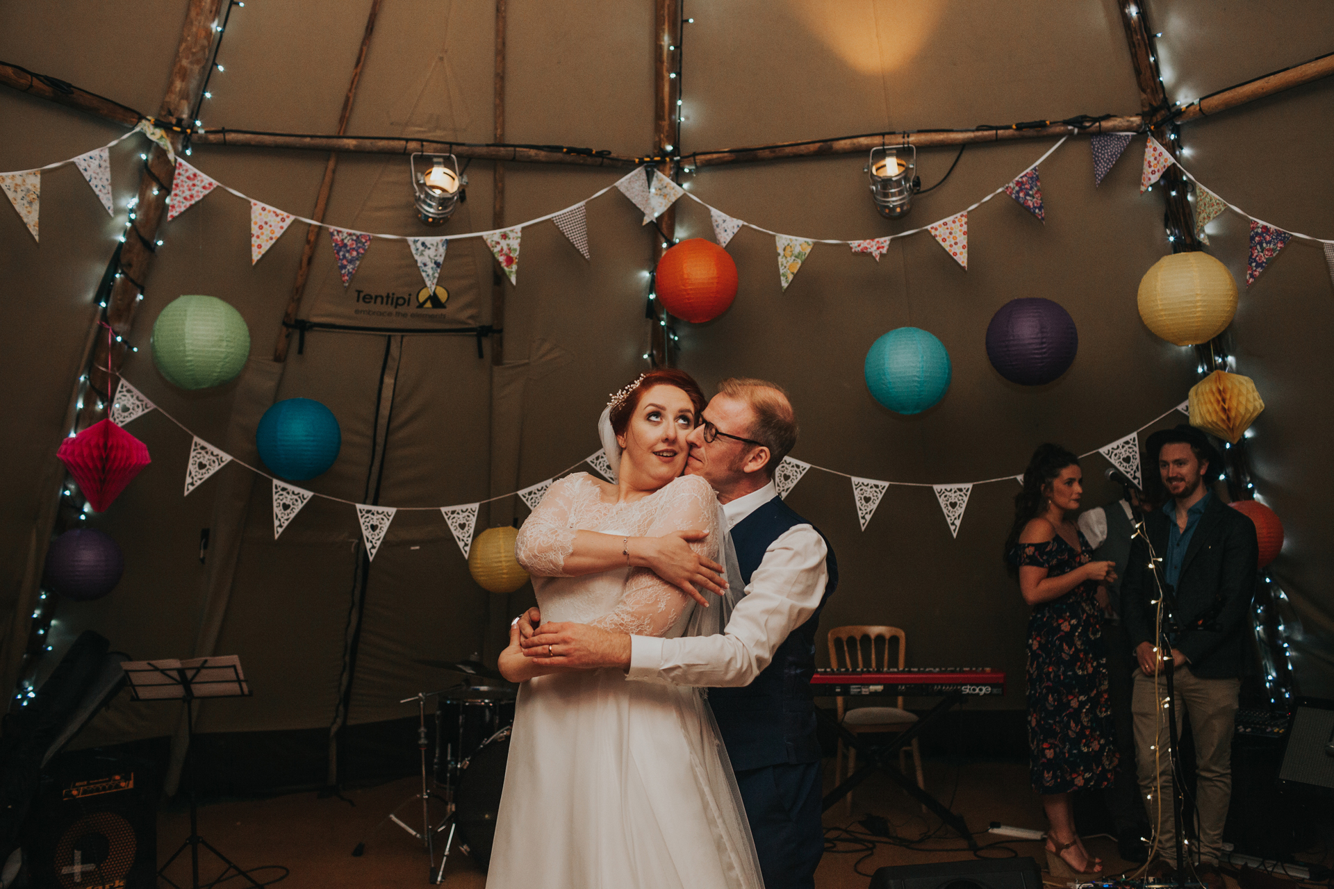 Bride and groom twirl and kiss on dance floor.