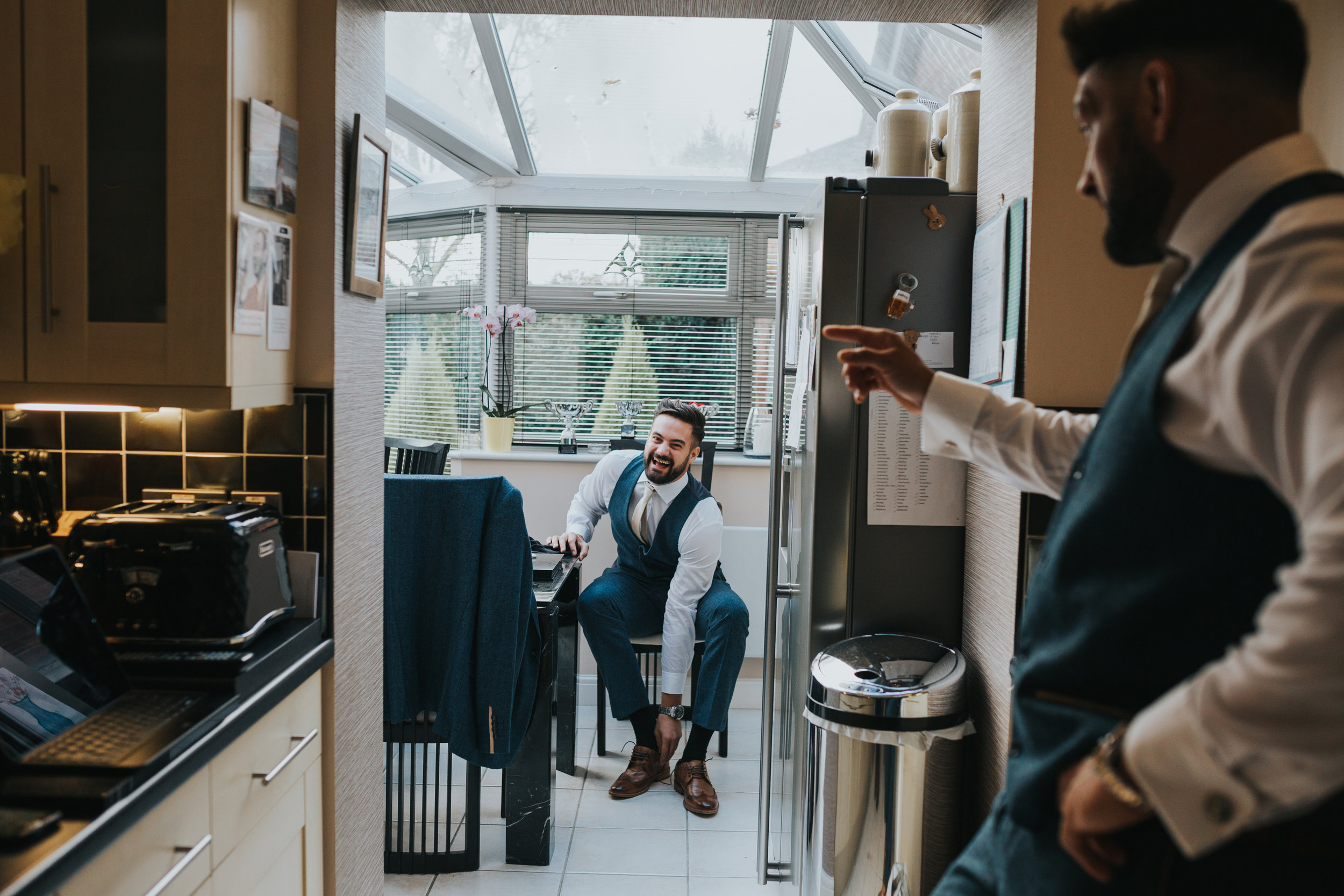 Groomsmen laughing together in the kitchen. 