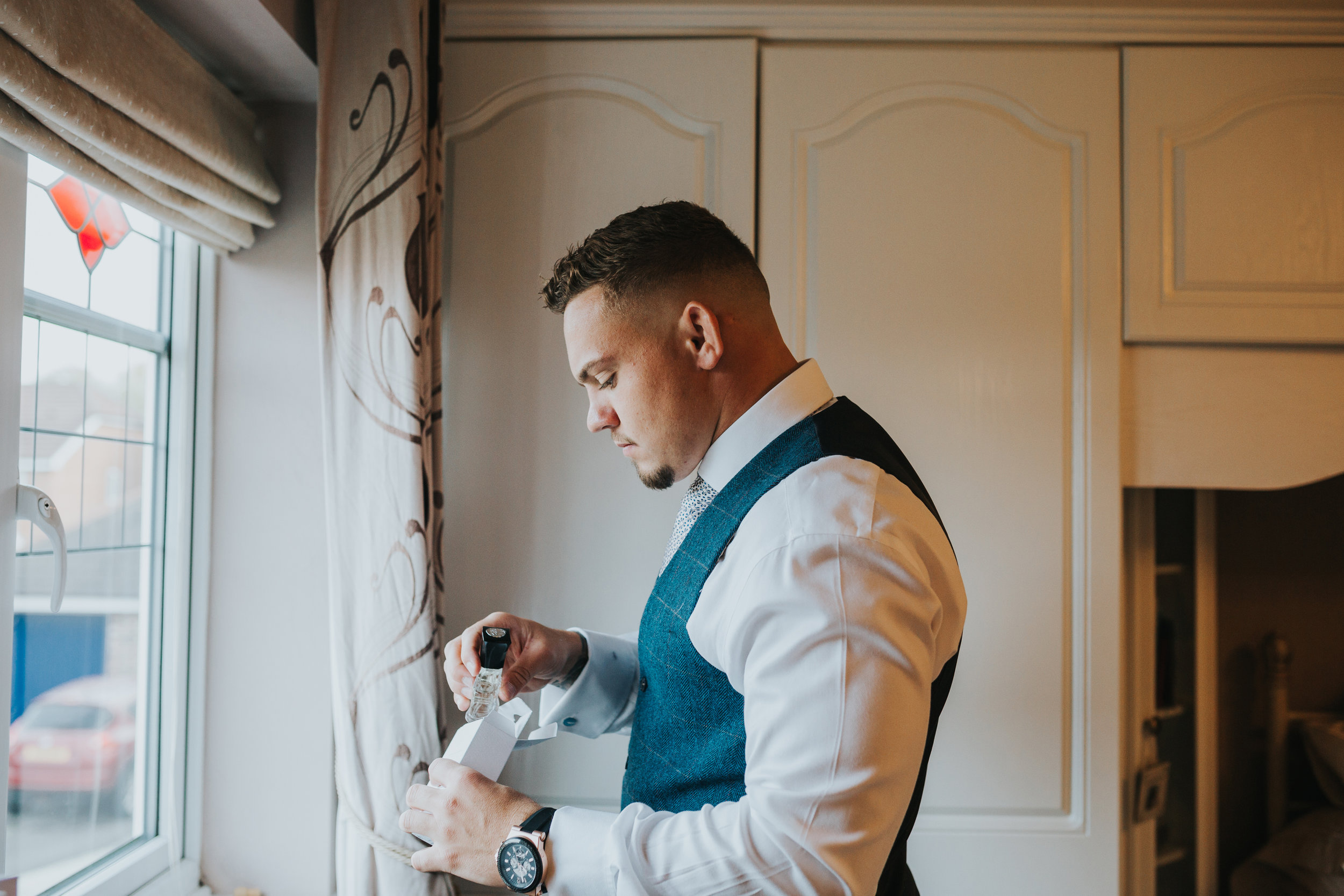 Groom putting on aftershave. 