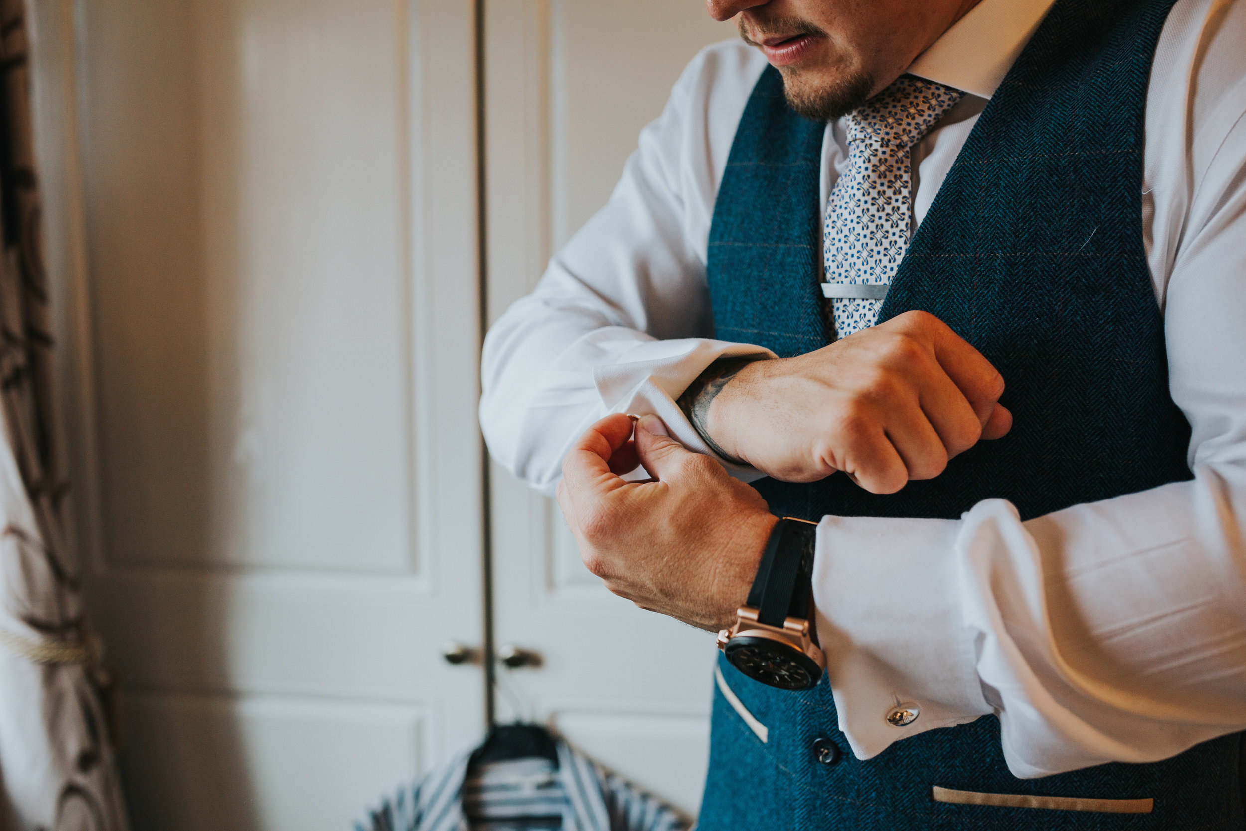 Groom putting on cuff links. 