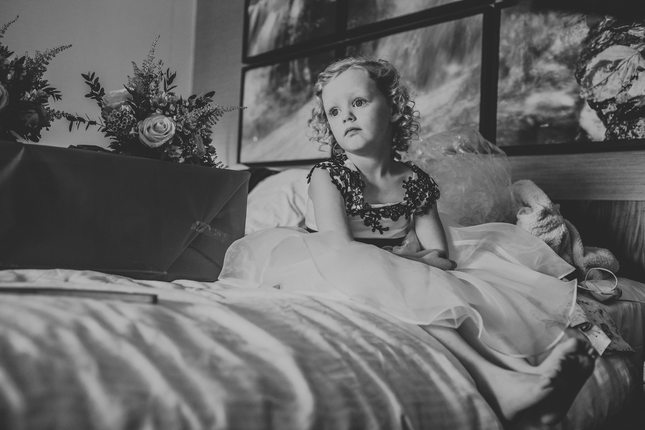 Flower girl sitting on the bed, photograph in black and white.