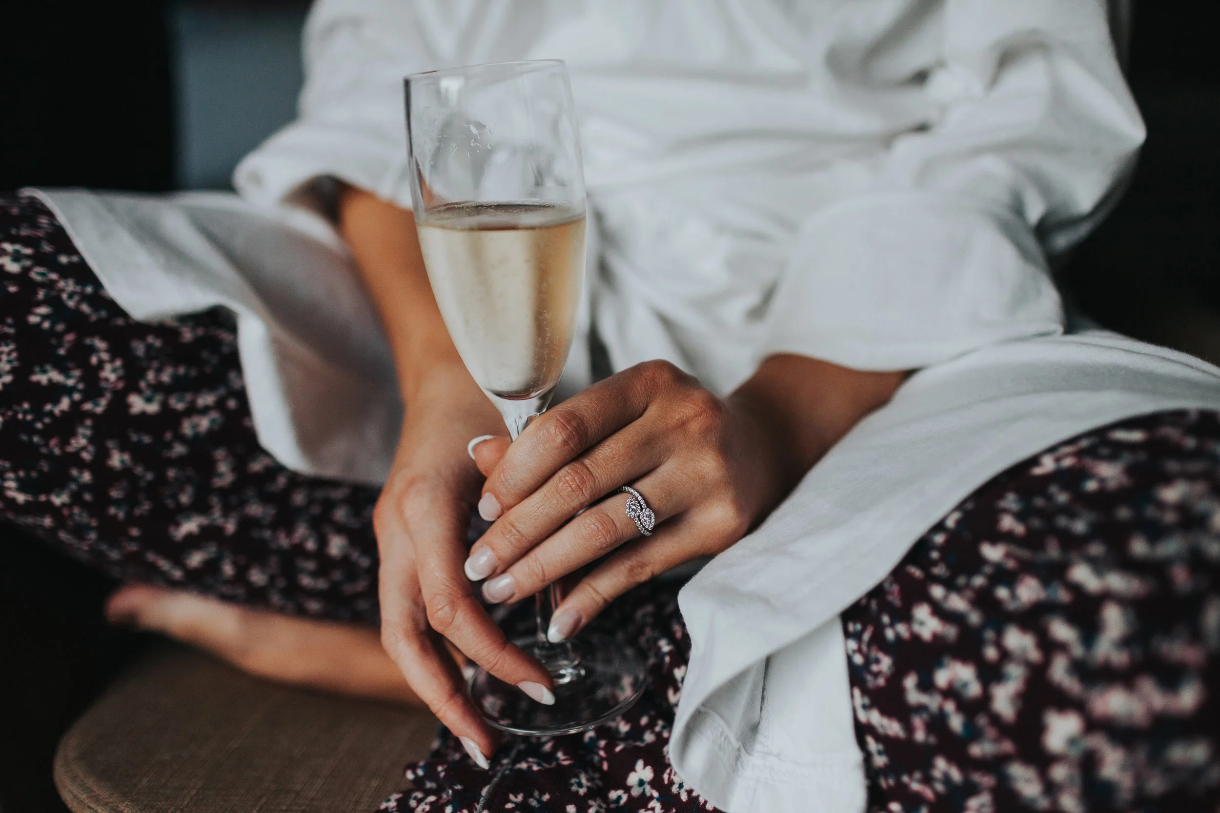 Bride holding champagne glass with her engagement ring showing. 
