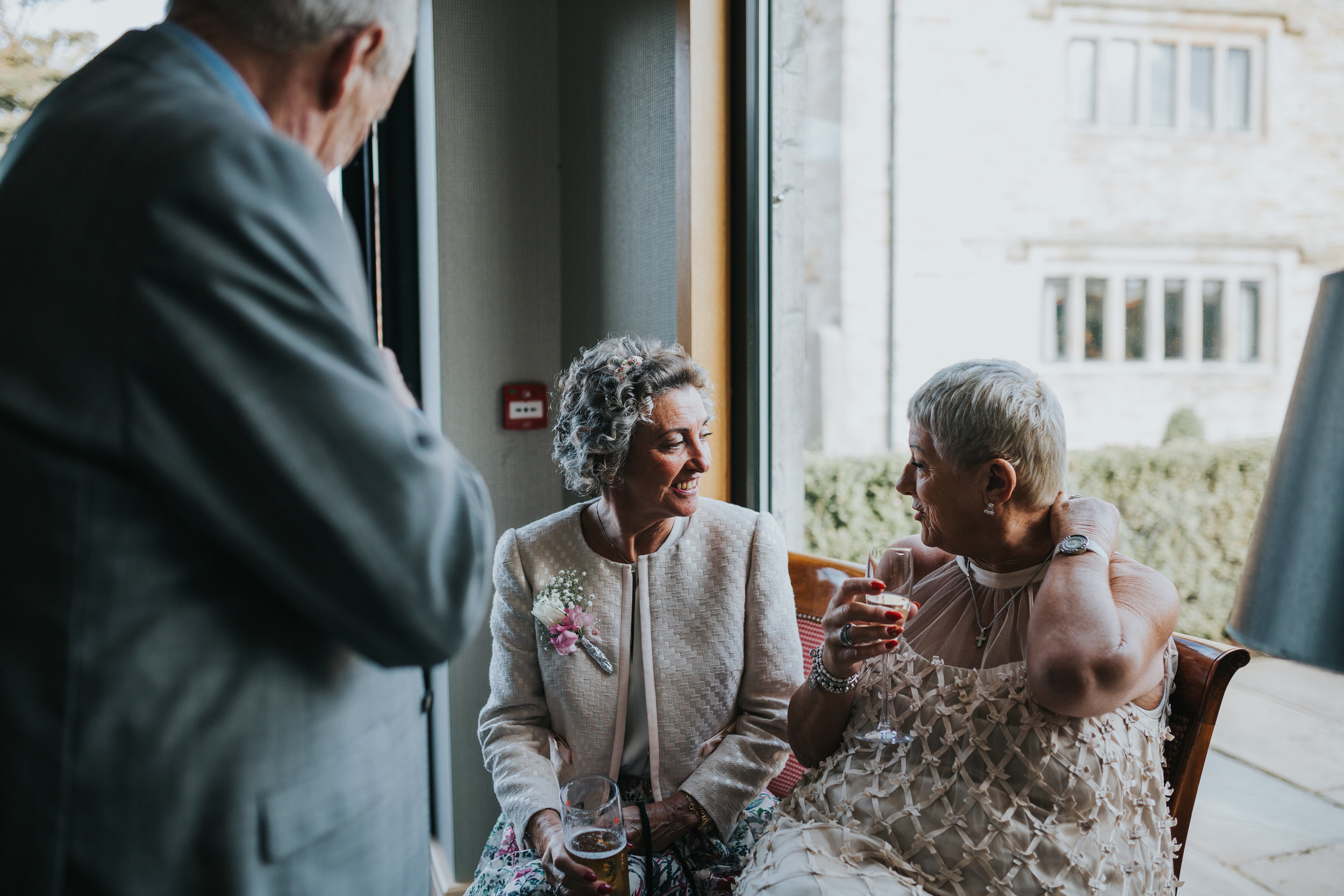 Wedding guests enjoy each others company next to a window. 