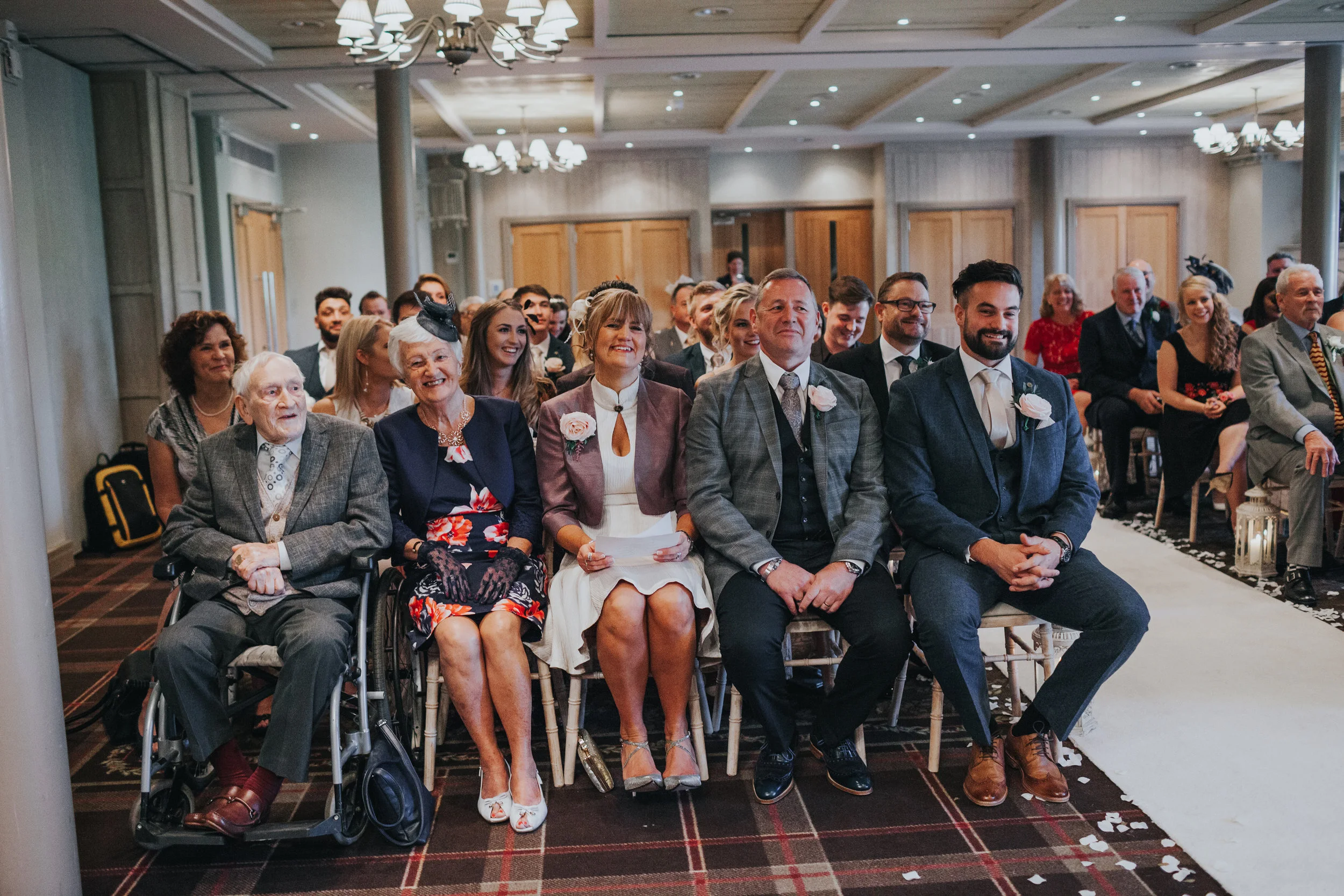 Wedding guests watch the ceremony with smiles of their faces. 
