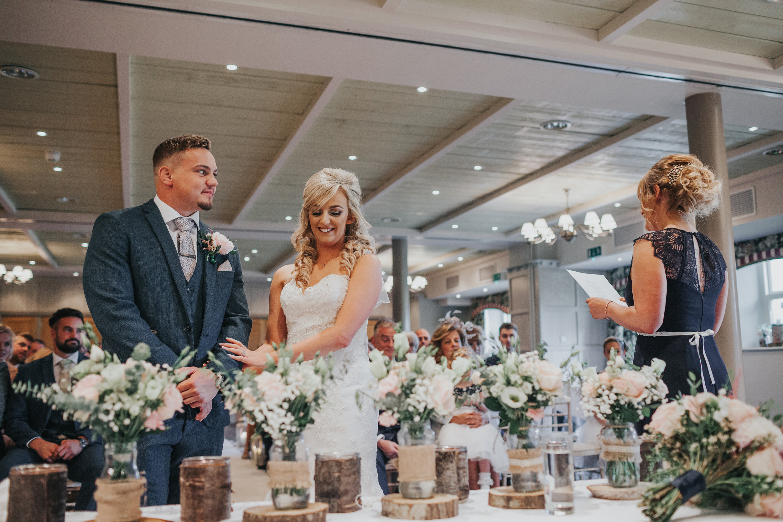 Bride and groom holding hands as one of their friends reads during their ceremony at Stanley House. 