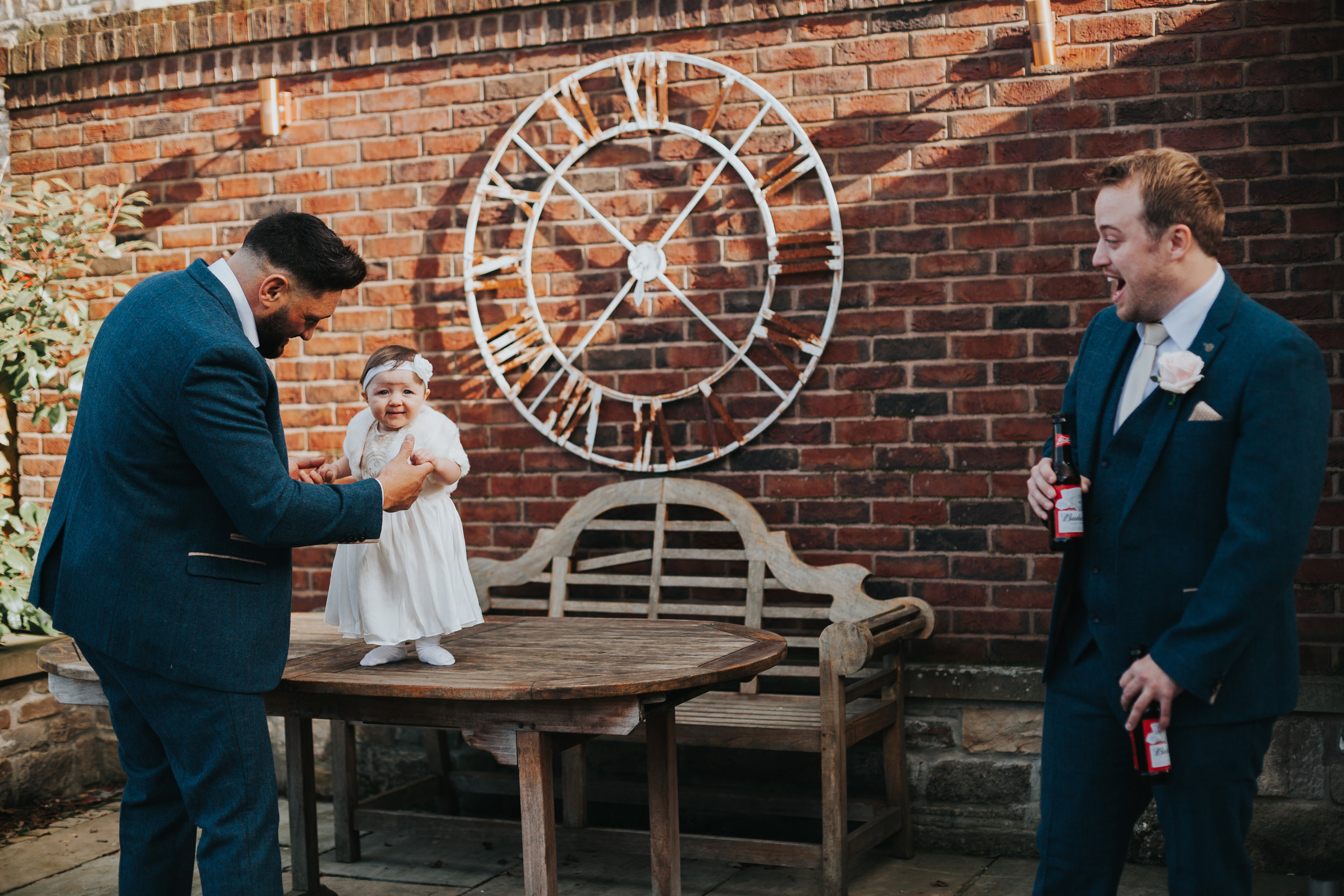 Little girl laughs with groomsmen. 