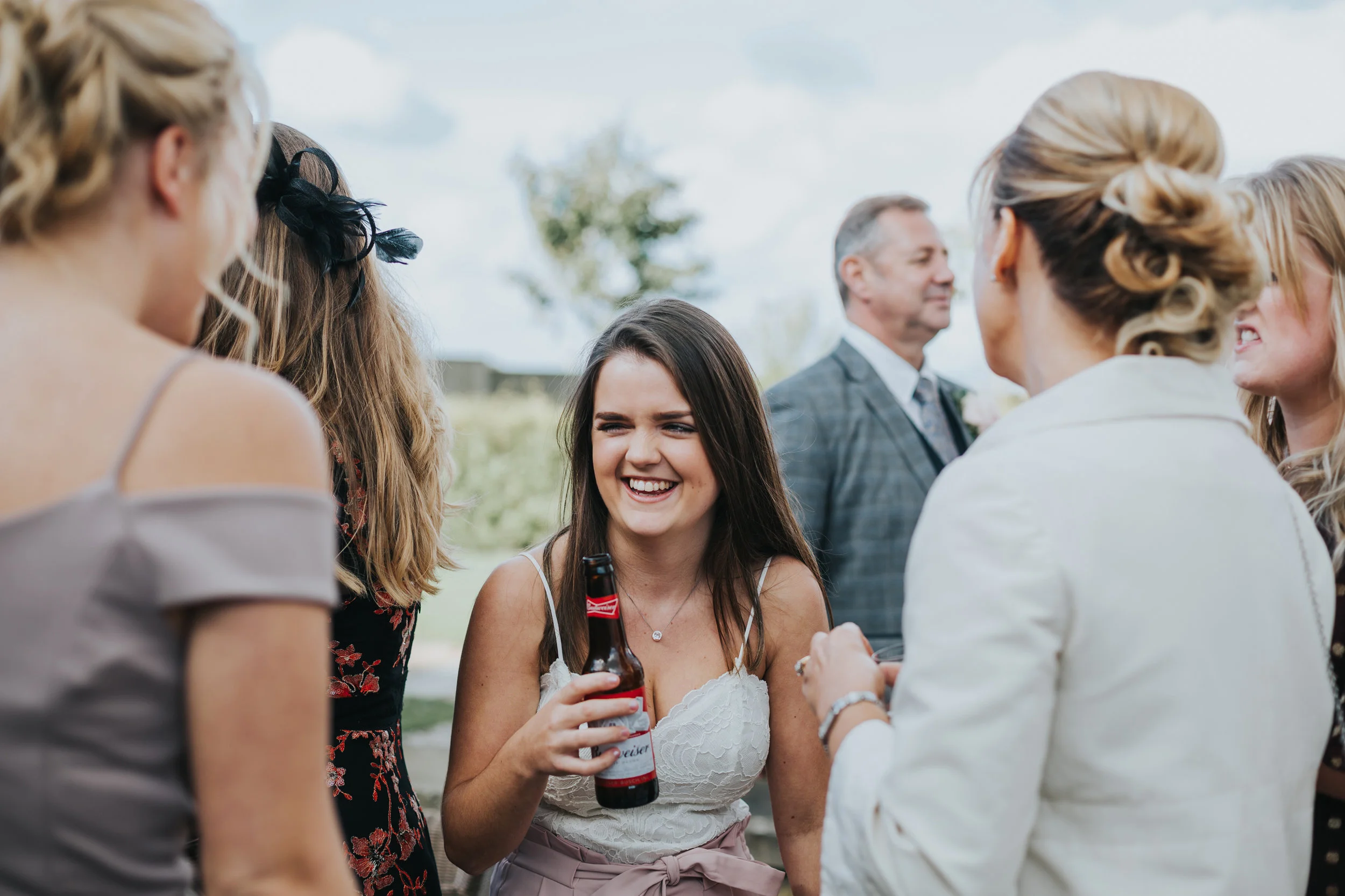 Girl has a beer with her mates at a wedding. 