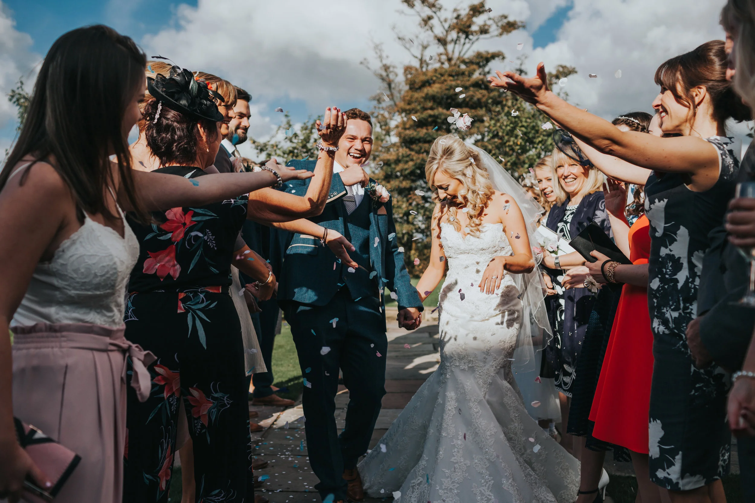 Bride and groom laugh as they are attacked with confetti. 