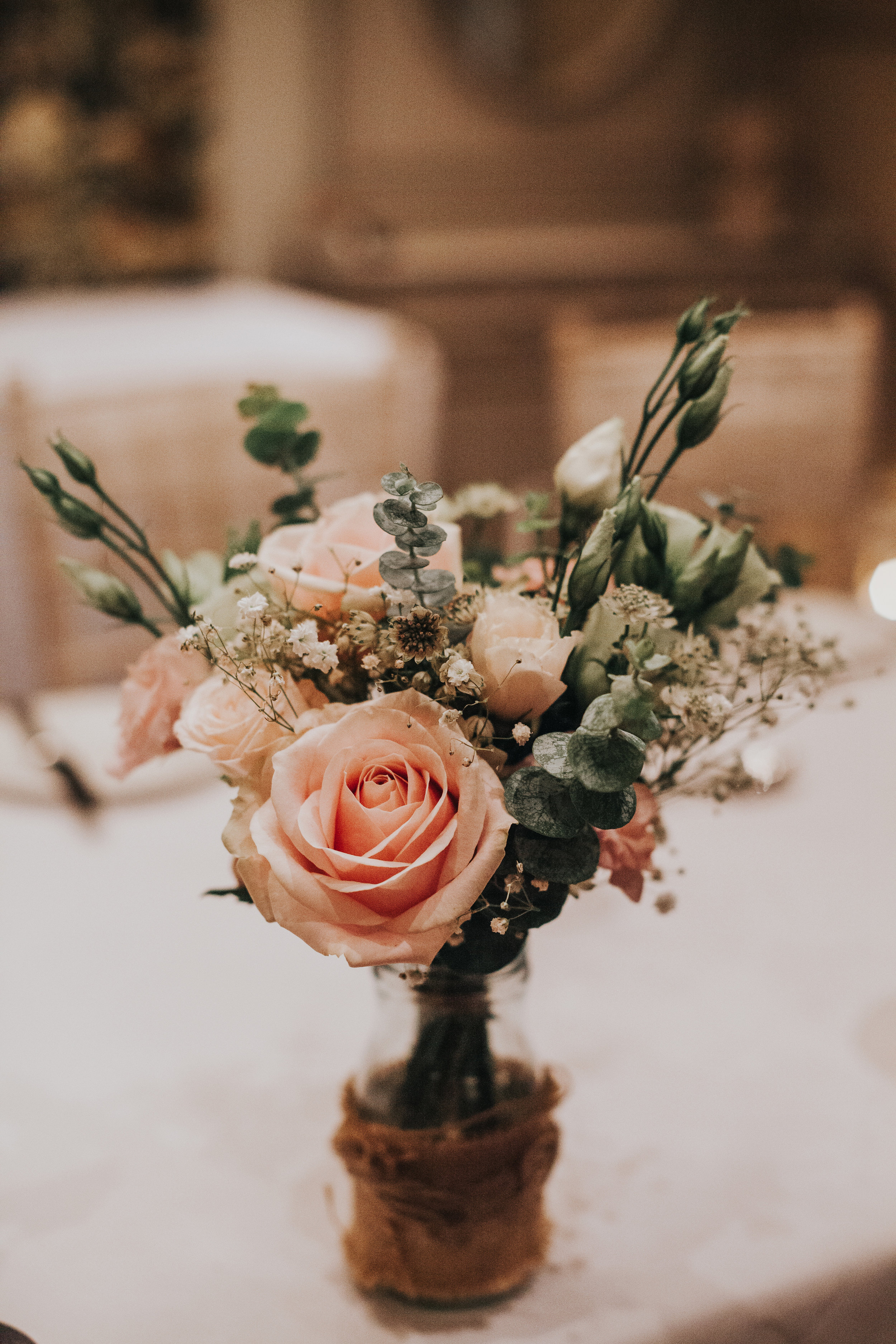 Pink roses and greenery in a jar as a table decoration. 