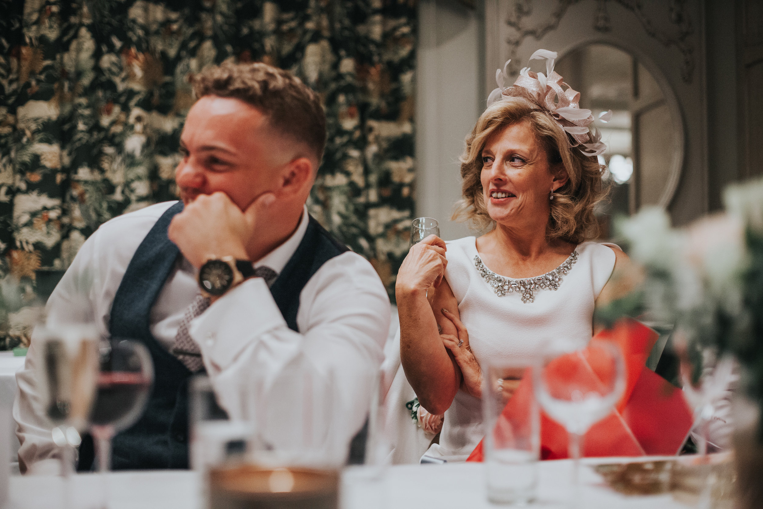 Mother of the bride smiles during best mans speech.