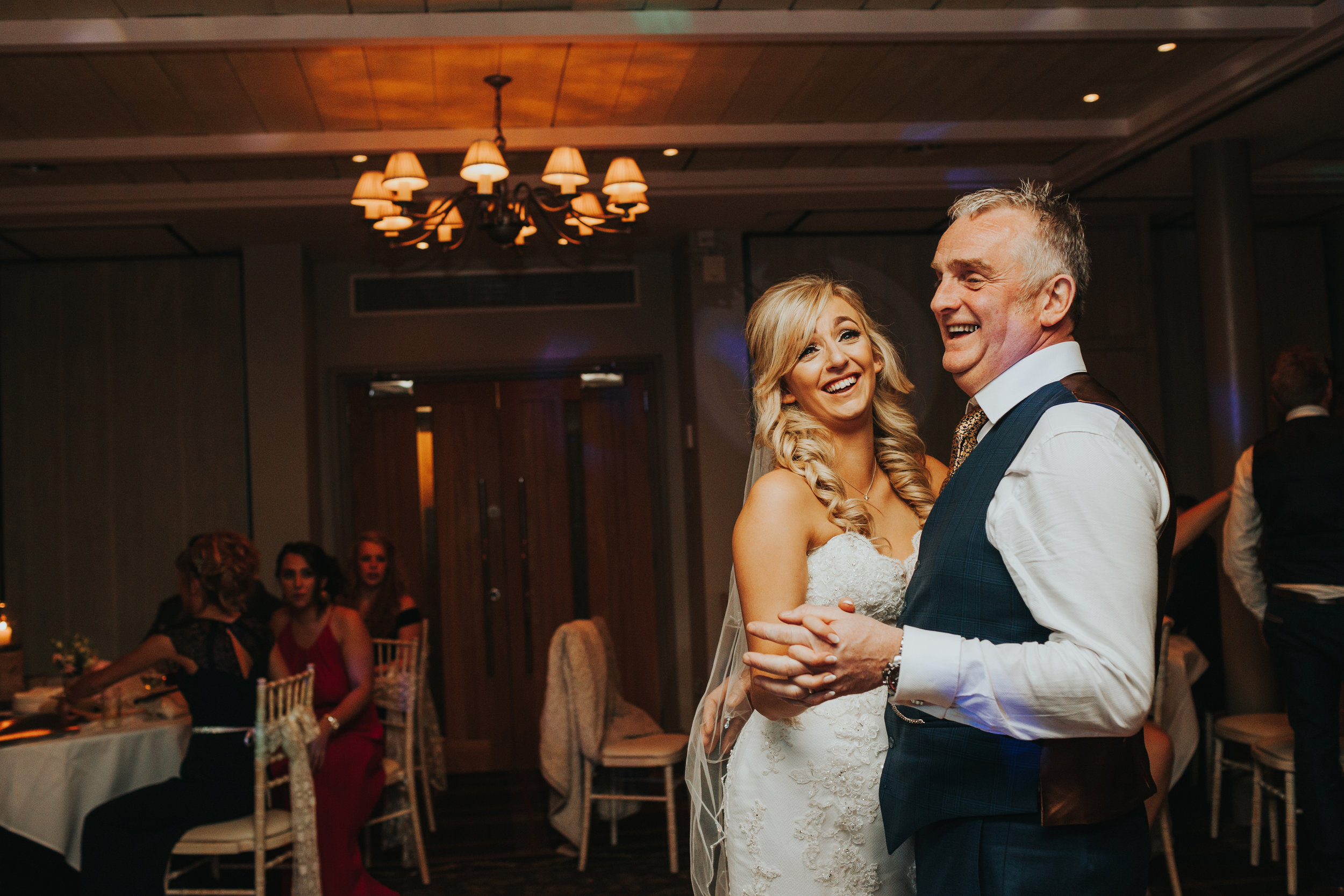 Bride dances with her Dad smiling. 