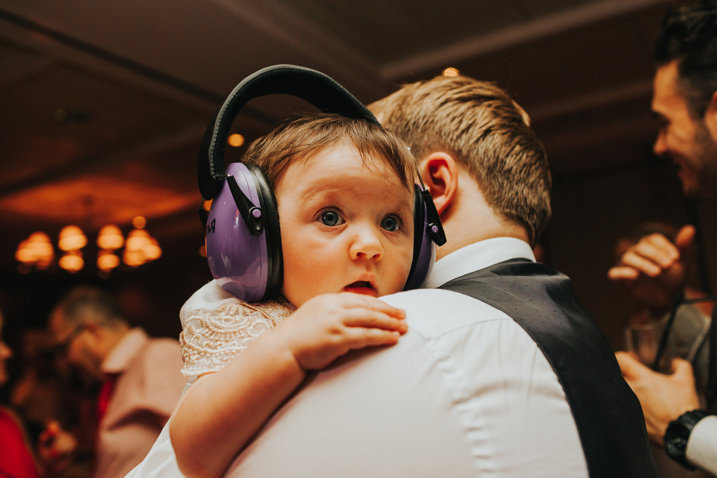 Cute baby with noise cancelling headphones on looking tired.
