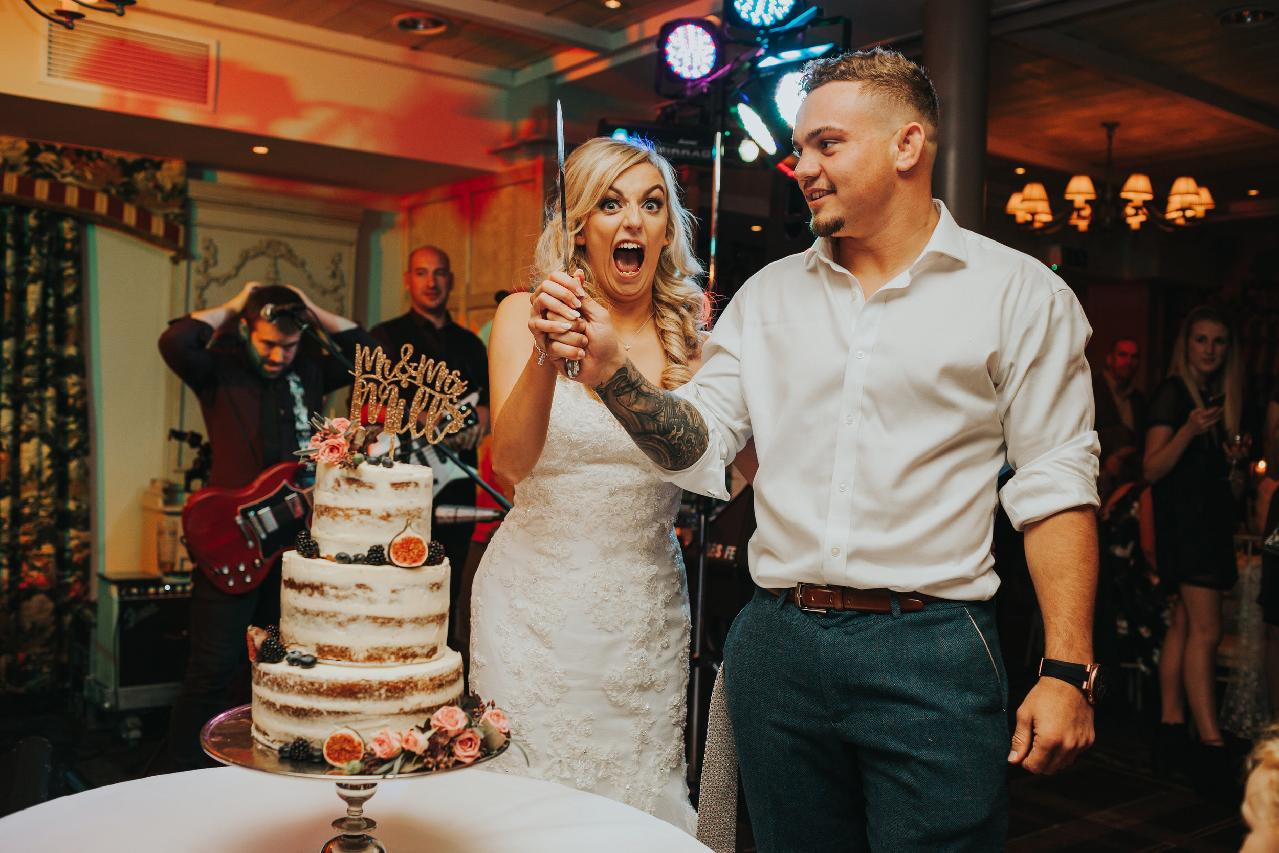 Bride pulls silly face as they cut the cake. 