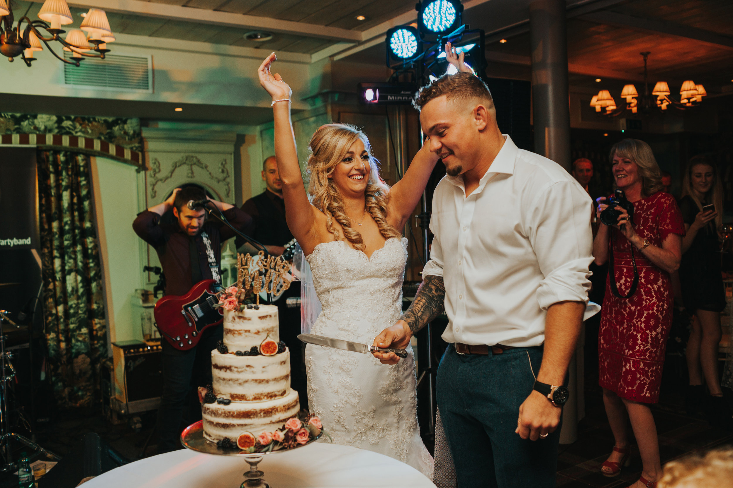 Bride celebrates as they cut the cake. 