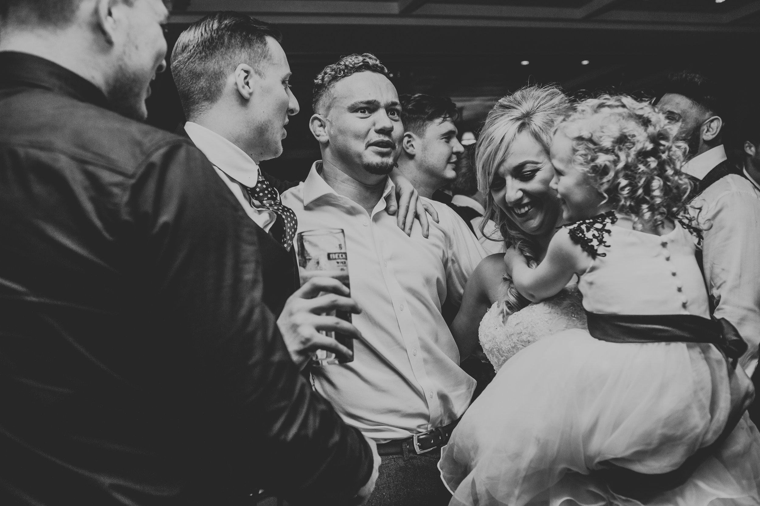 Bride picks up flower girl smiling. 