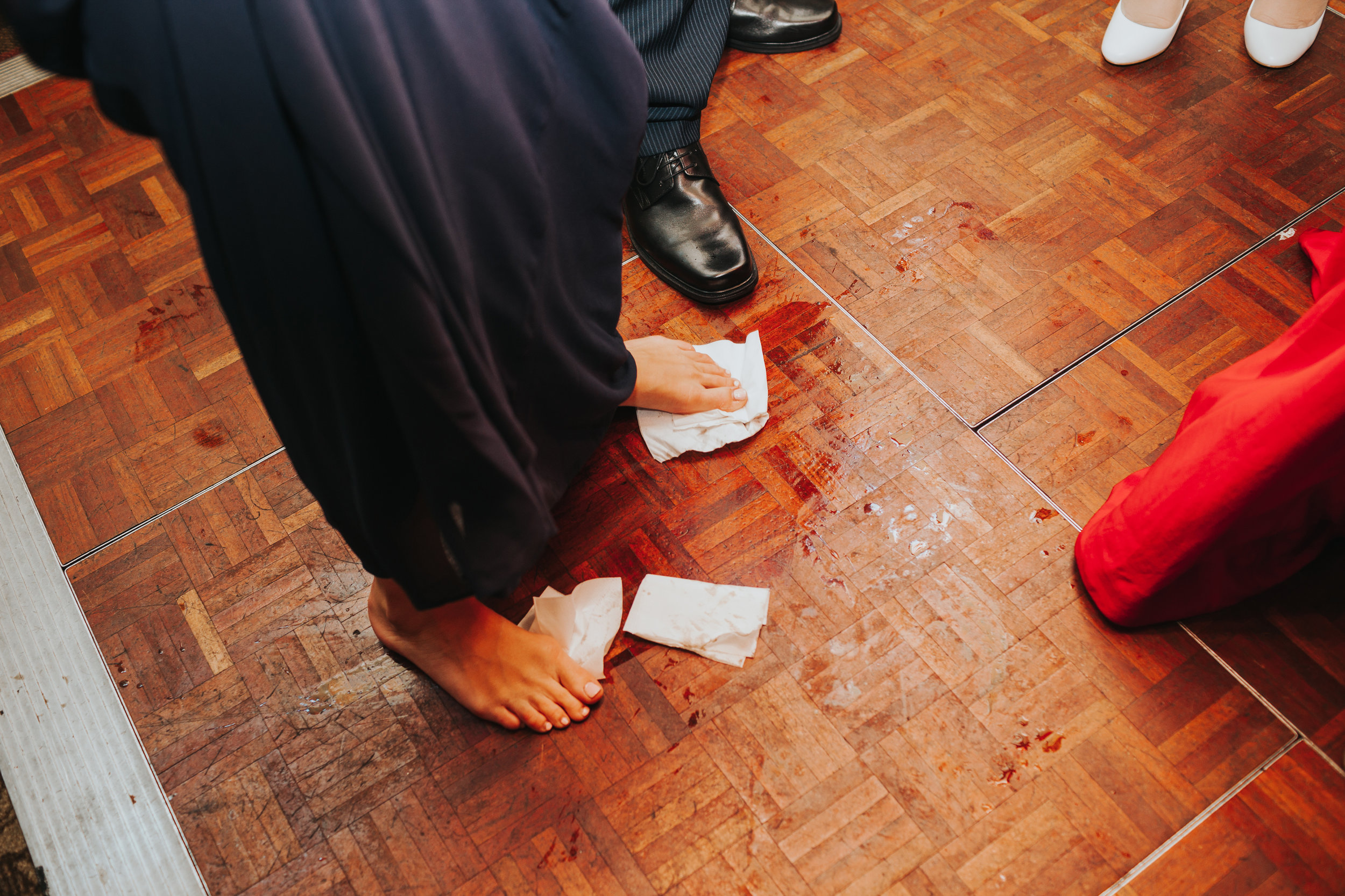 Bridesmaid uses napkin feet to wipe up the floor. 