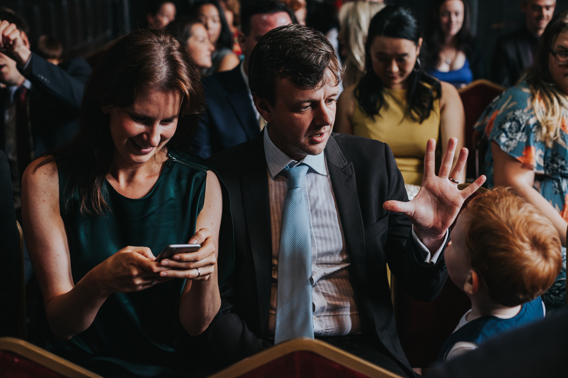 Wedding guest does a magic trick for his son inside the ceremony room at Chetham Library. 