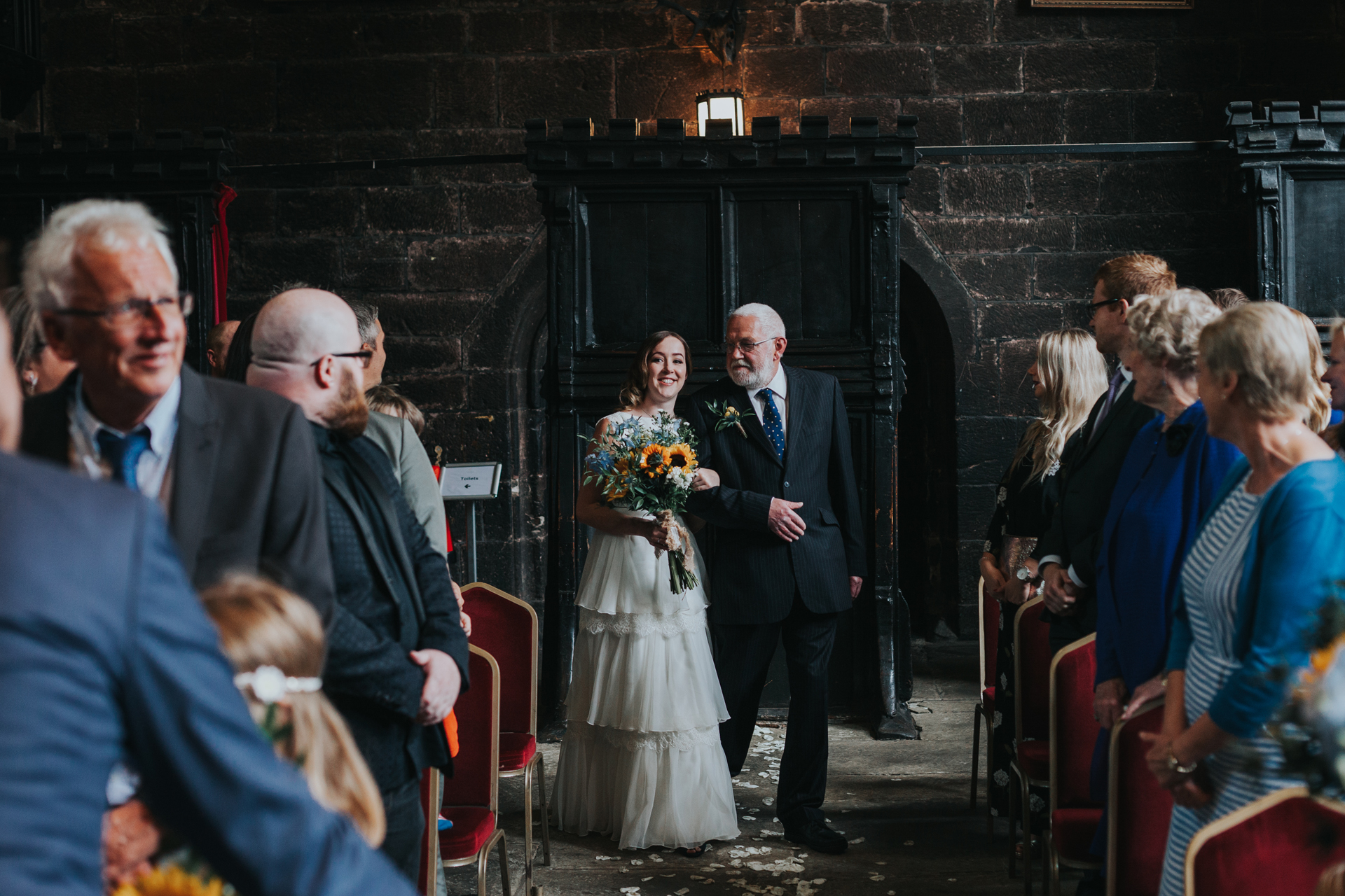 Bride is walked down the aisle by her father at Chetham's Library. 