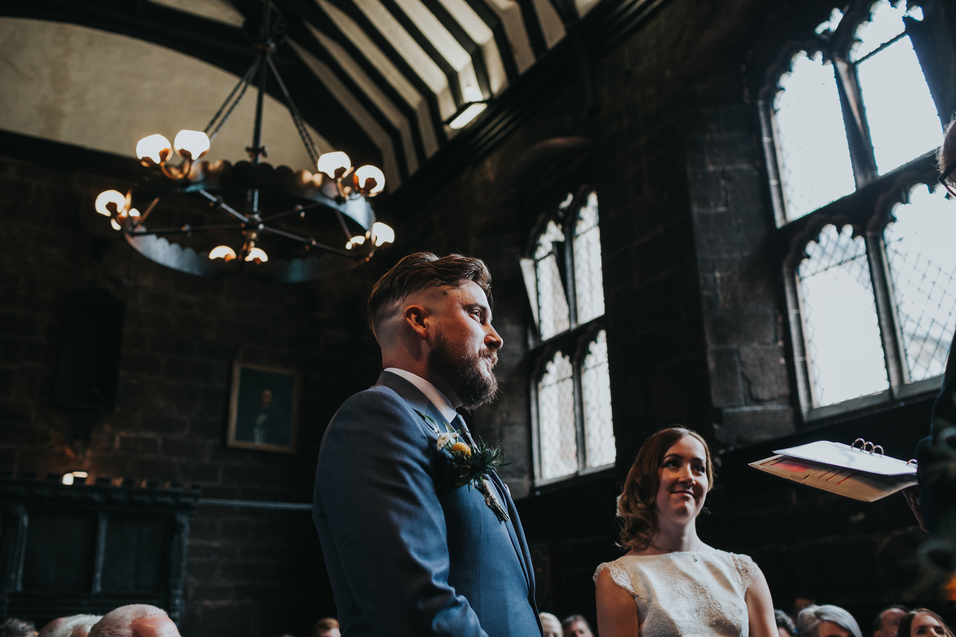 Groom stands next to bride at Chetham's Library Manchester. 