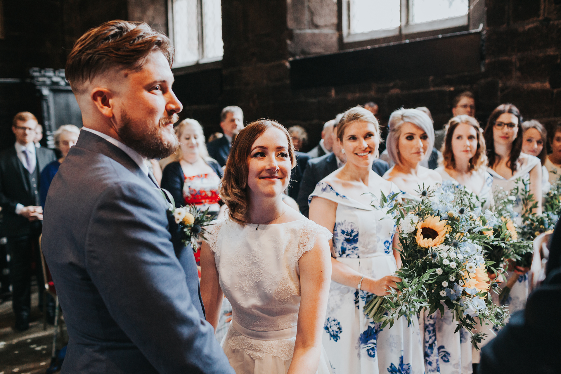 Bride and Groom stand together with a row of Bridesmaids behind them at Chatham Library Manchester. 