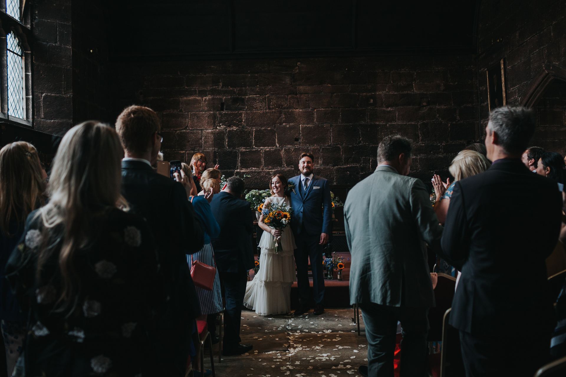 Bride and Groom stand married in front of their wedding guests at Chetham's Library Manchester. 