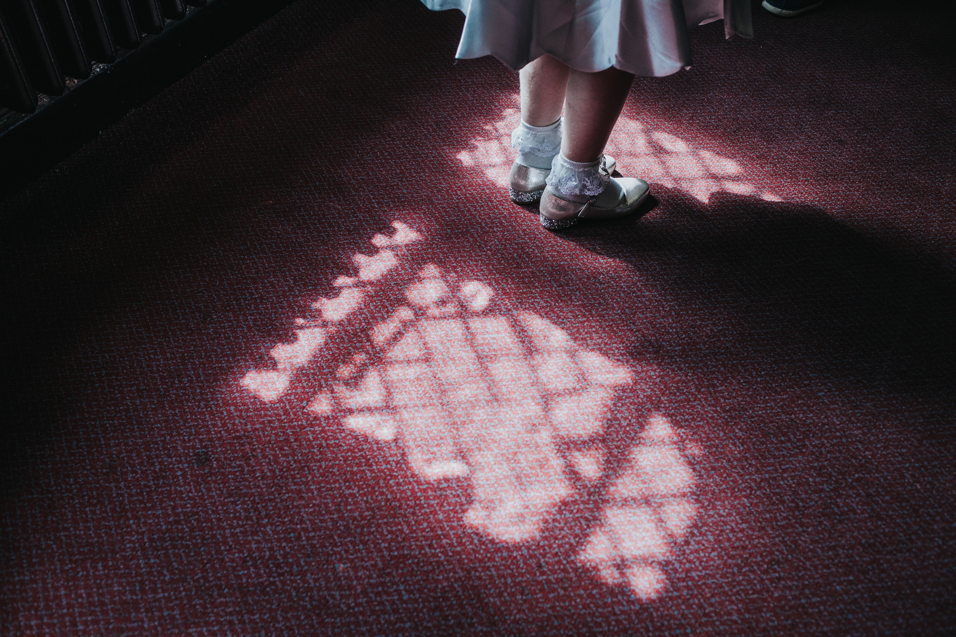 Bridesmaid stands in window light at Chetham's Library Manchester.