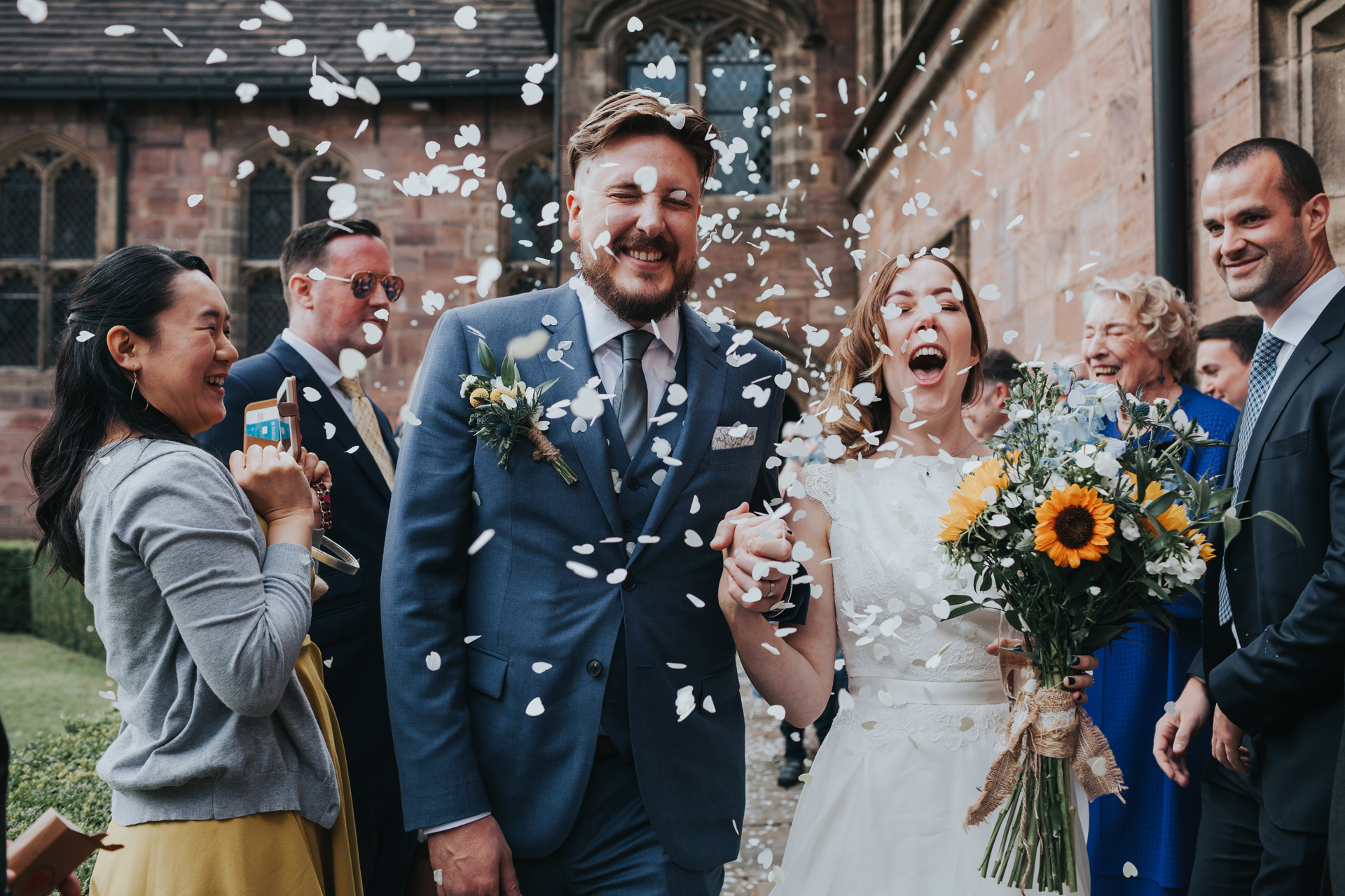 Bride and Groom have confetti thrown at them by their wedding guests outside Chetham Library and look very excited about it!