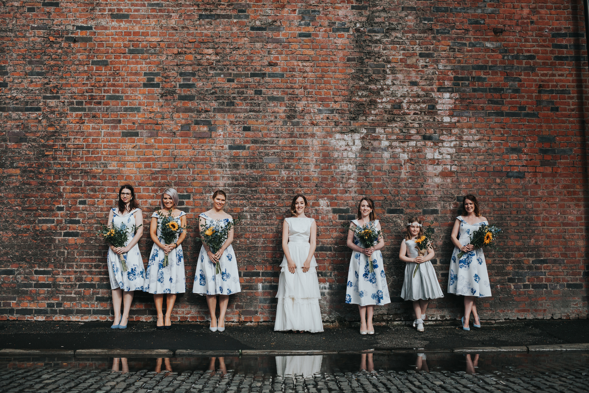 Bride and Bridesmaids stand in front of puddle outside Lock 91.  