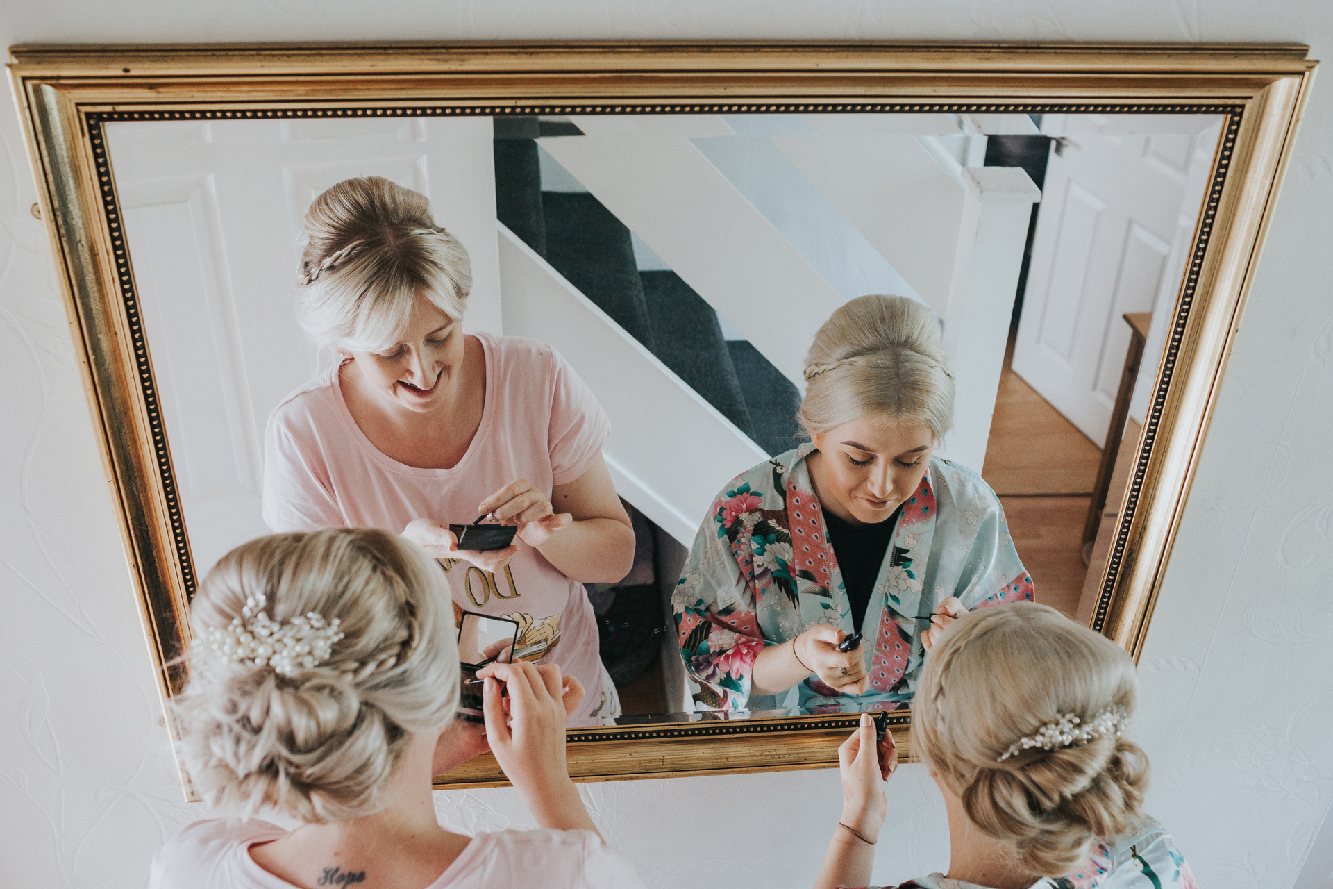 Bridesmaids putting make up on in the mirror at home in Manchester